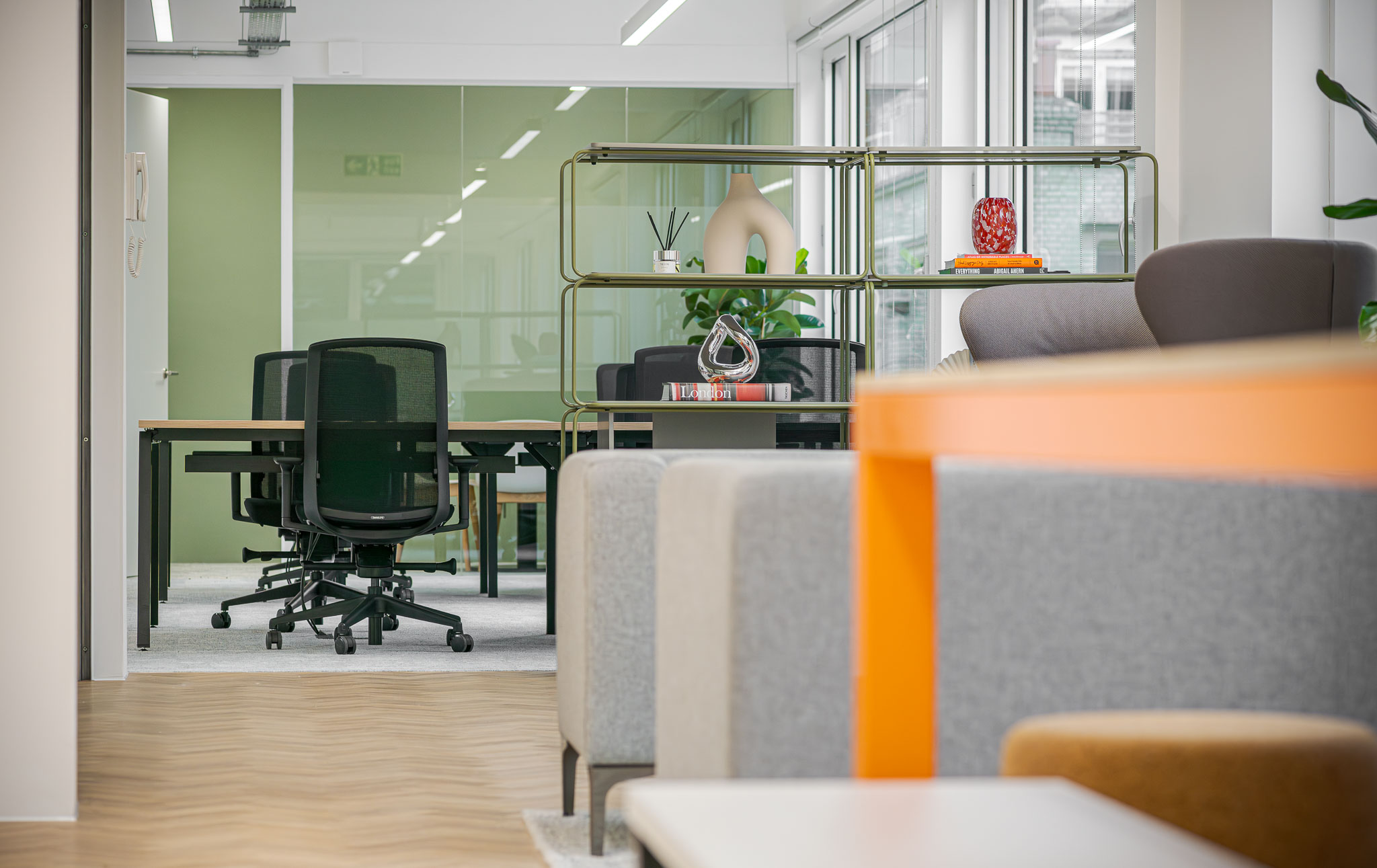 Berry Street workspace featuring a sage green wall, grey soft seating areas and a glass wall.