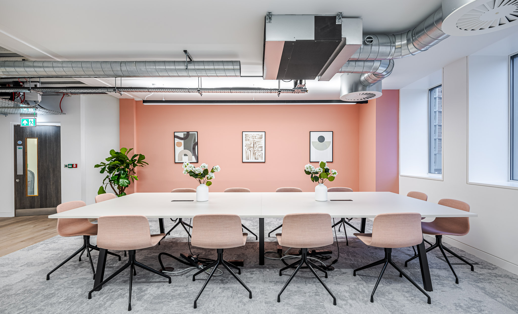 Asset Management workspace with pink walls and chairs accompanied by white floral pieces creating an airy space.