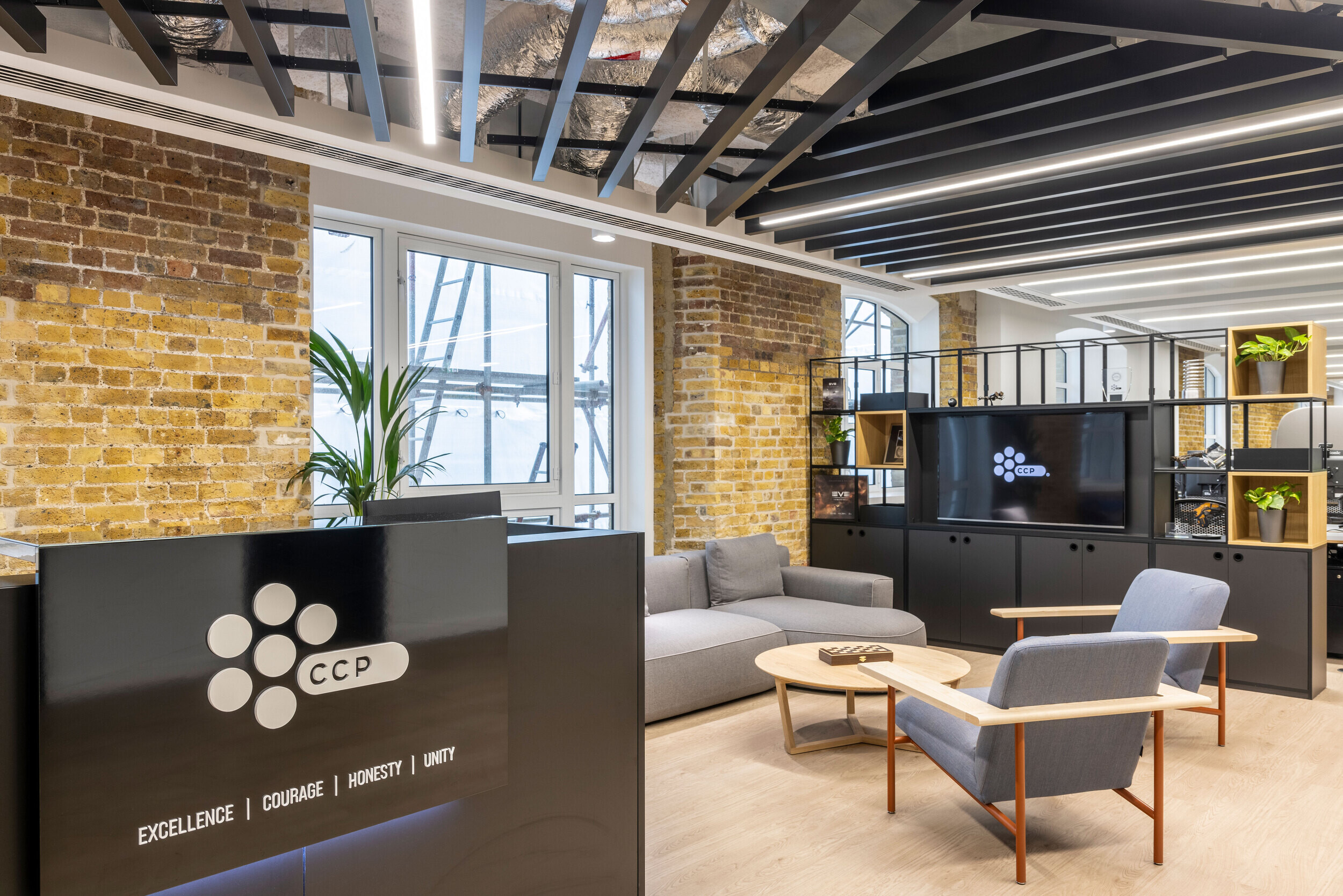 Comfortable breakout space in CCP Games’ office, featuring soft seating, exposed brick walls, and stylish shelving units.