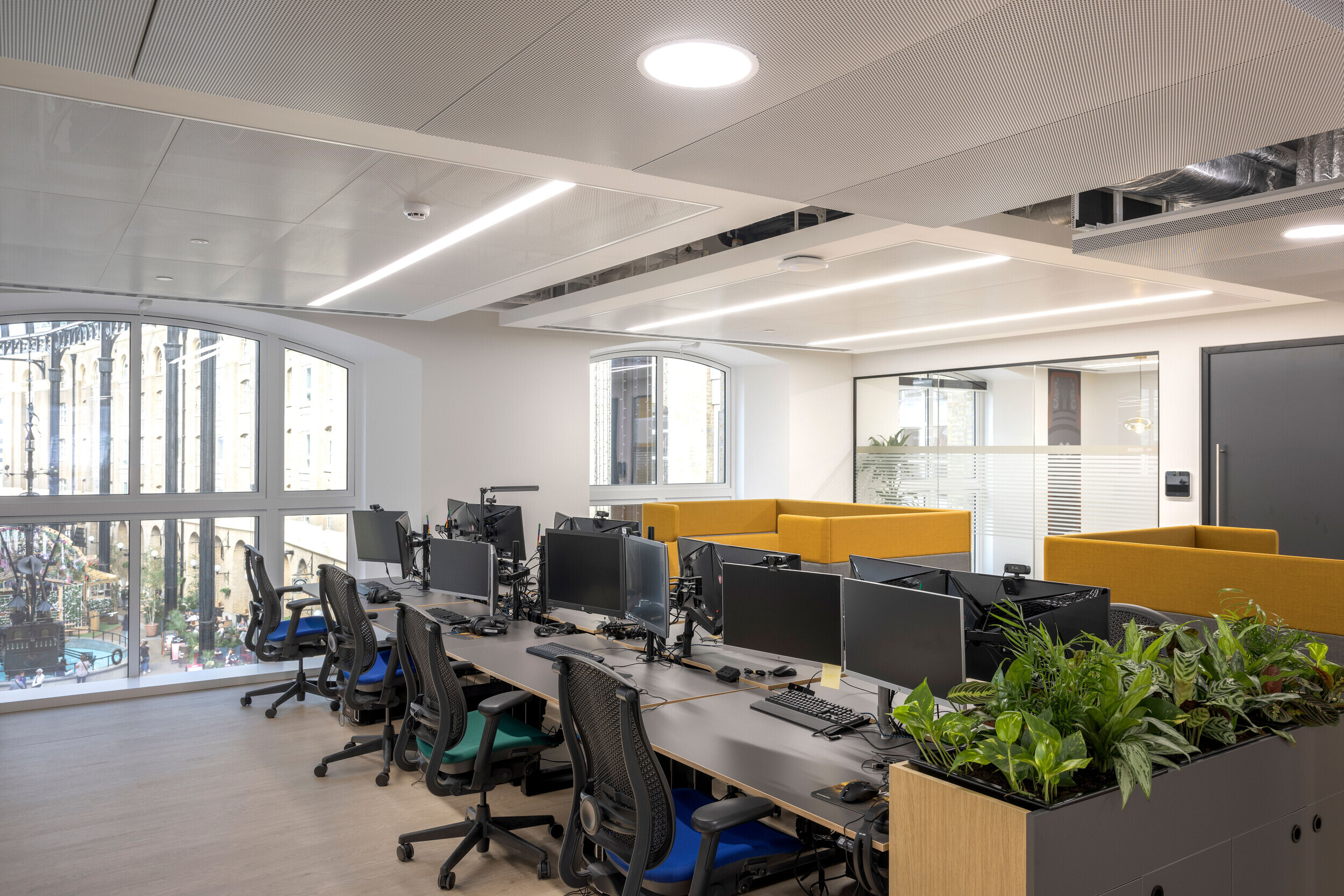 Bright workstations in CCP Games’ office, designed by Two, with large windows overlooking London’s iconic Hay’s Galleria.