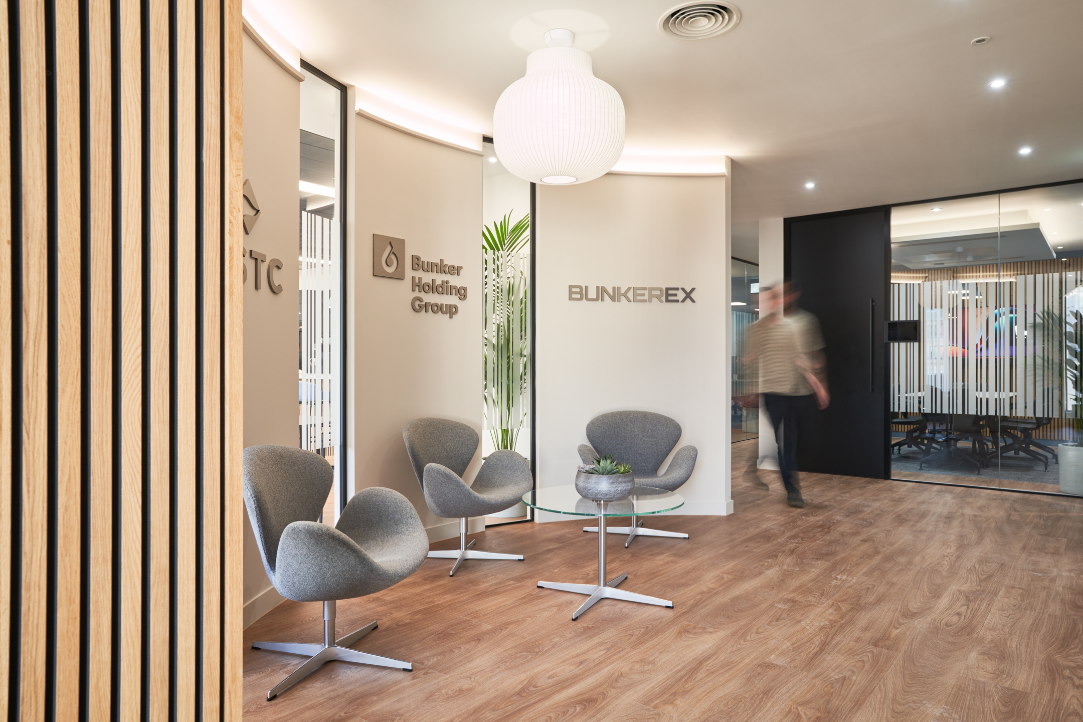 Reception area at KPI Ocean Connect, showcasing Two’s innovative office design with stylish grey seating, wooden slats, and branded signage.