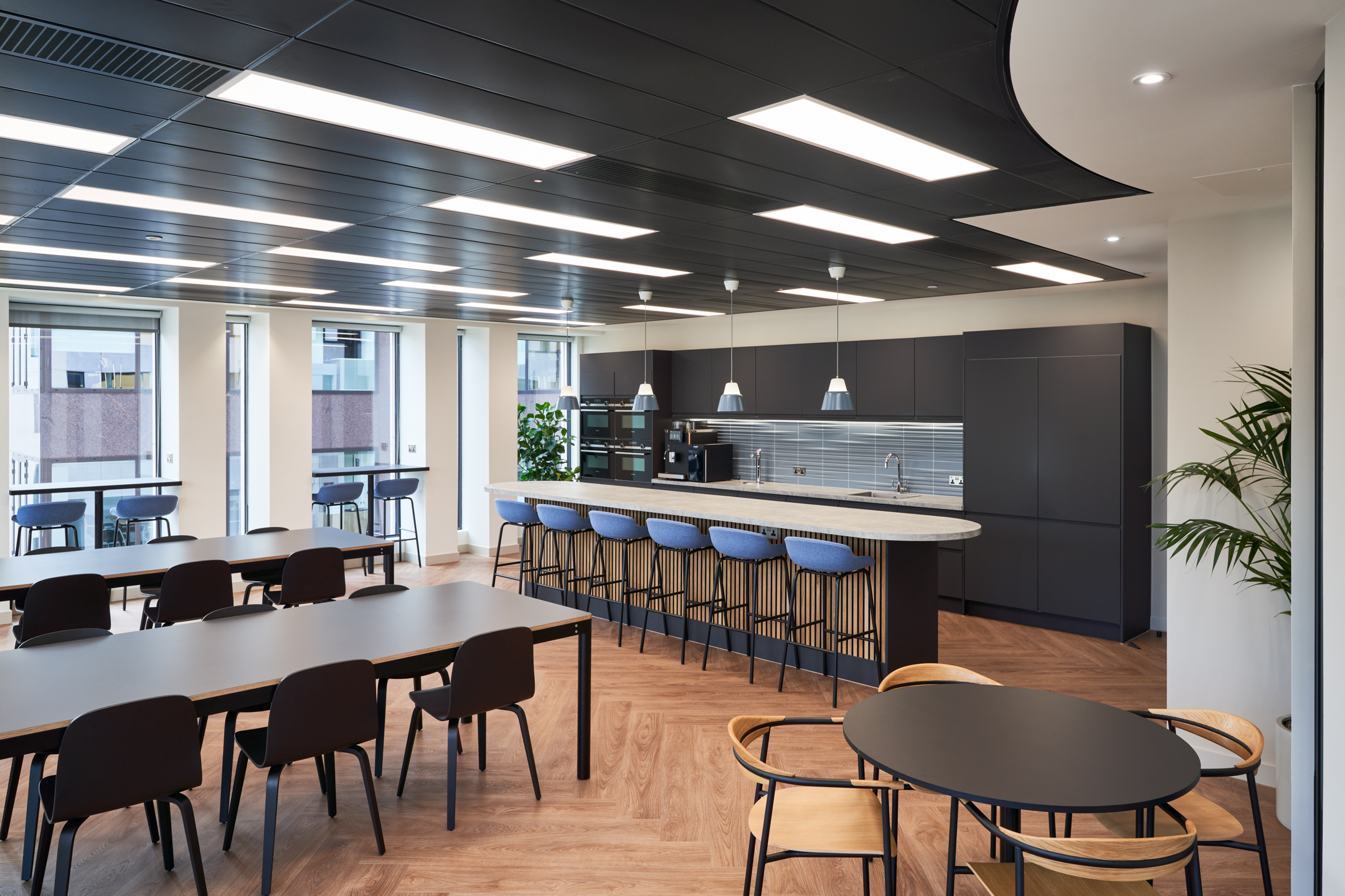 Contemporary office kitchen at KPI Ocean Connect, with black cabinets, a marble countertop, and pendant lighting, designed by Two for a stylish workspace.