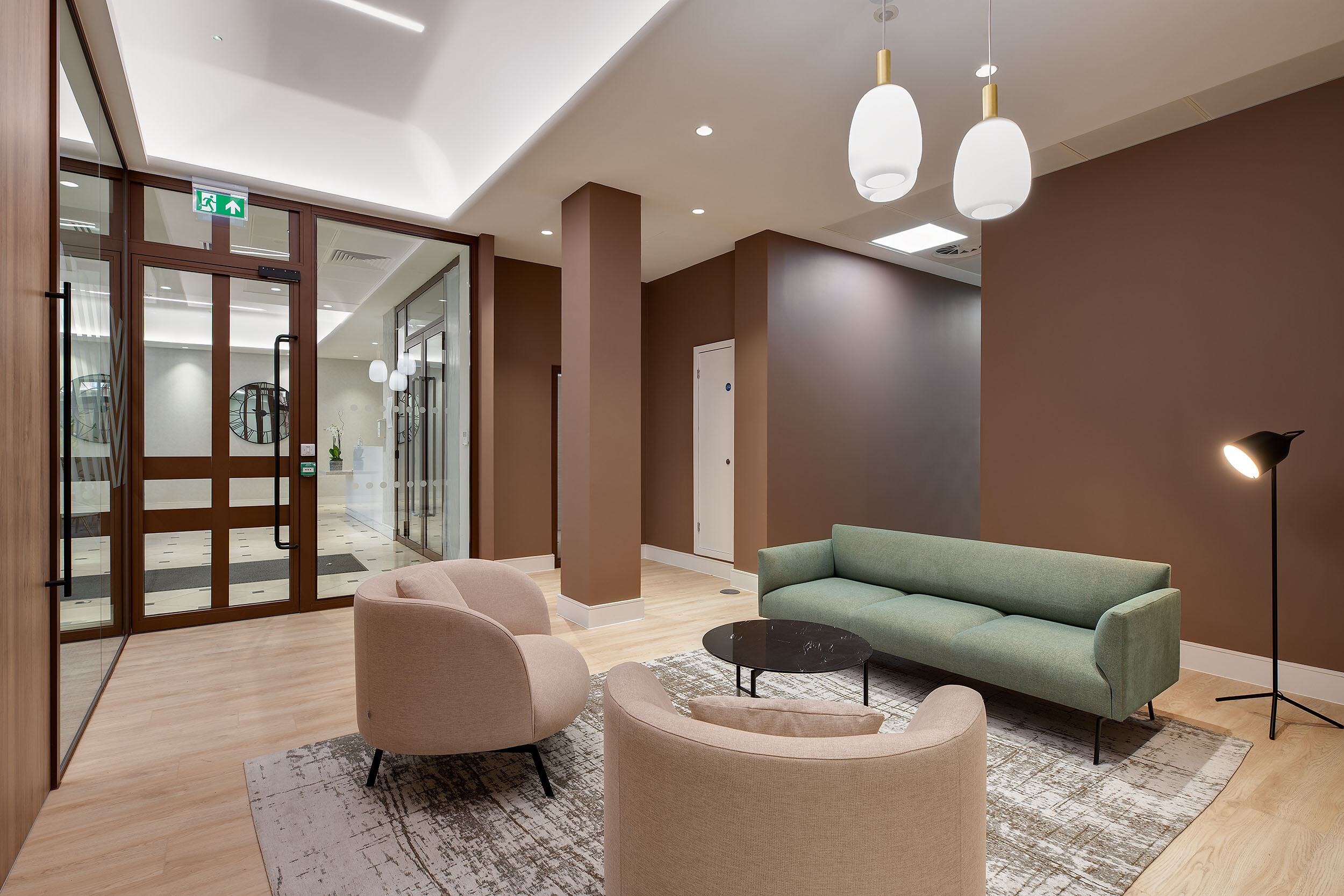 A welcoming office lounge at 123 Pall Mall, featuring modern furniture with a mix of neutral and green tones, creating a relaxed space for informal meetings.