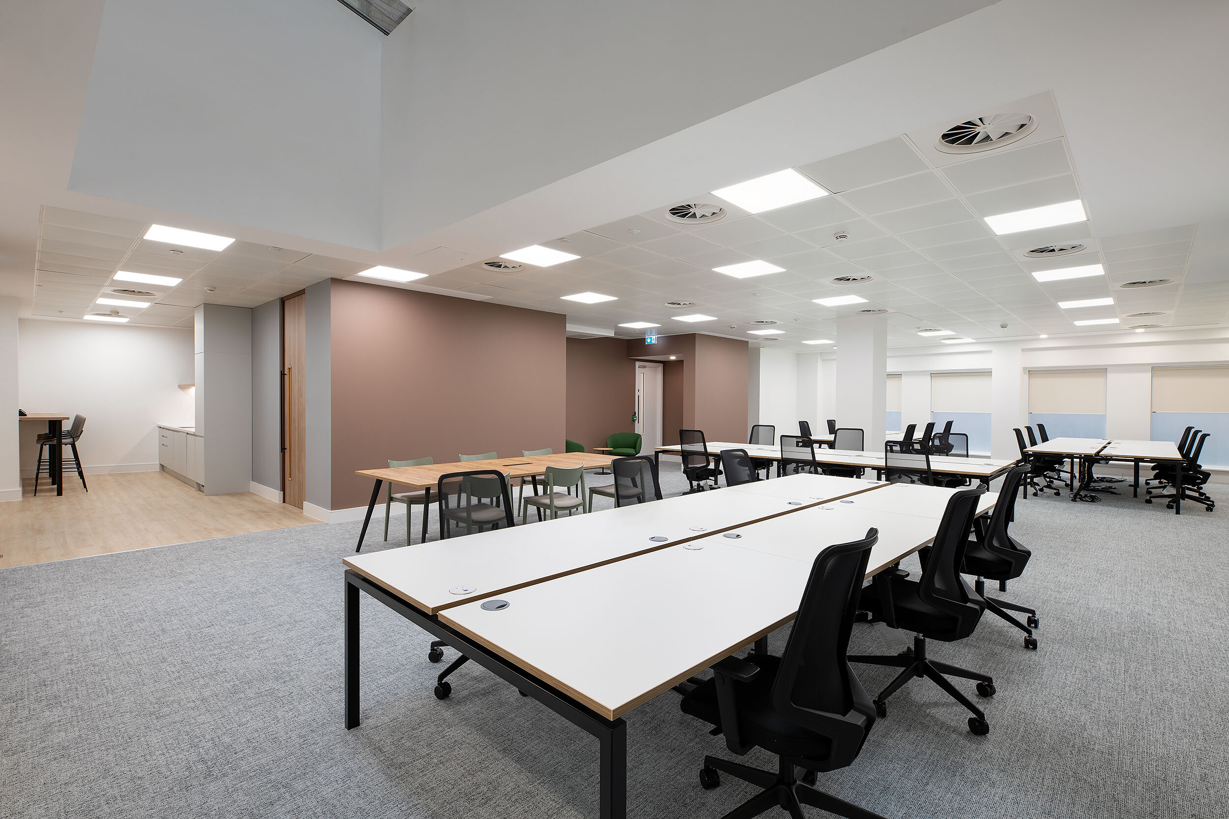 An open-plan workspace designed by Two, featuring long rows of desks, ergonomic chairs, and a teapoint area, providing a flexible and functional office environment.