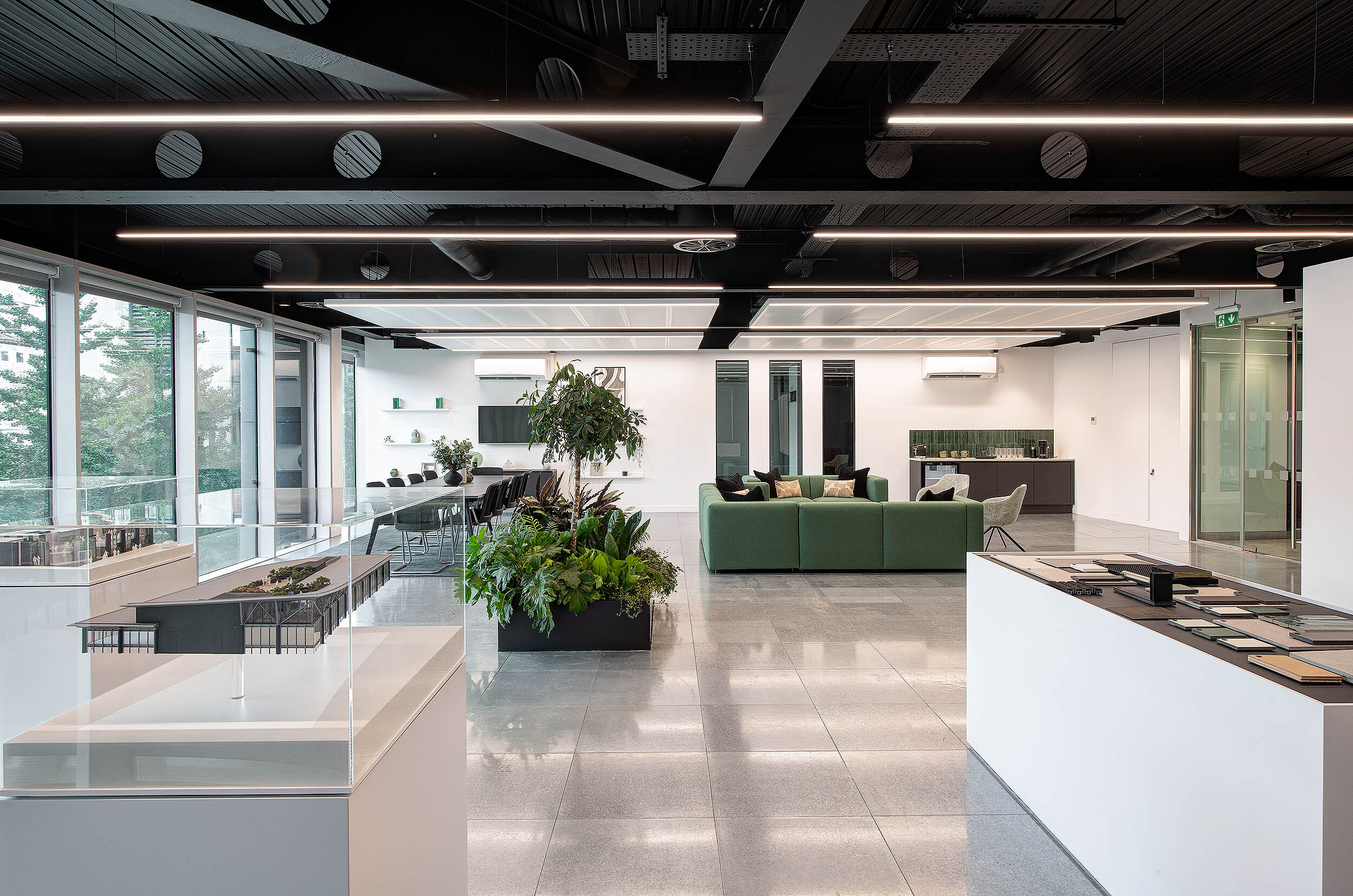 Open-plan office at 95 Queen Victoria Street designed by Two, featuring biophilic elements, green seating, and a display of architectural models and samples.