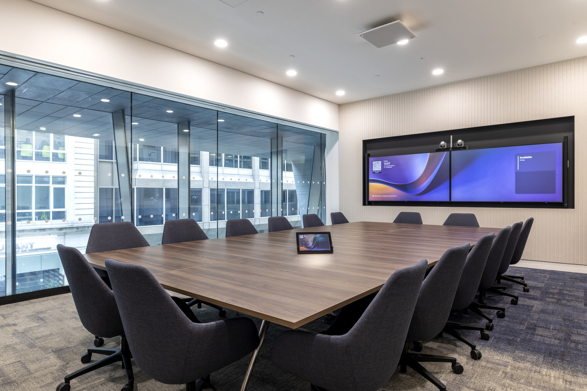 Executive boardroom at CMC Markets designed by Two, featuring advanced dual-screen technology and a sleek walnut conference table.