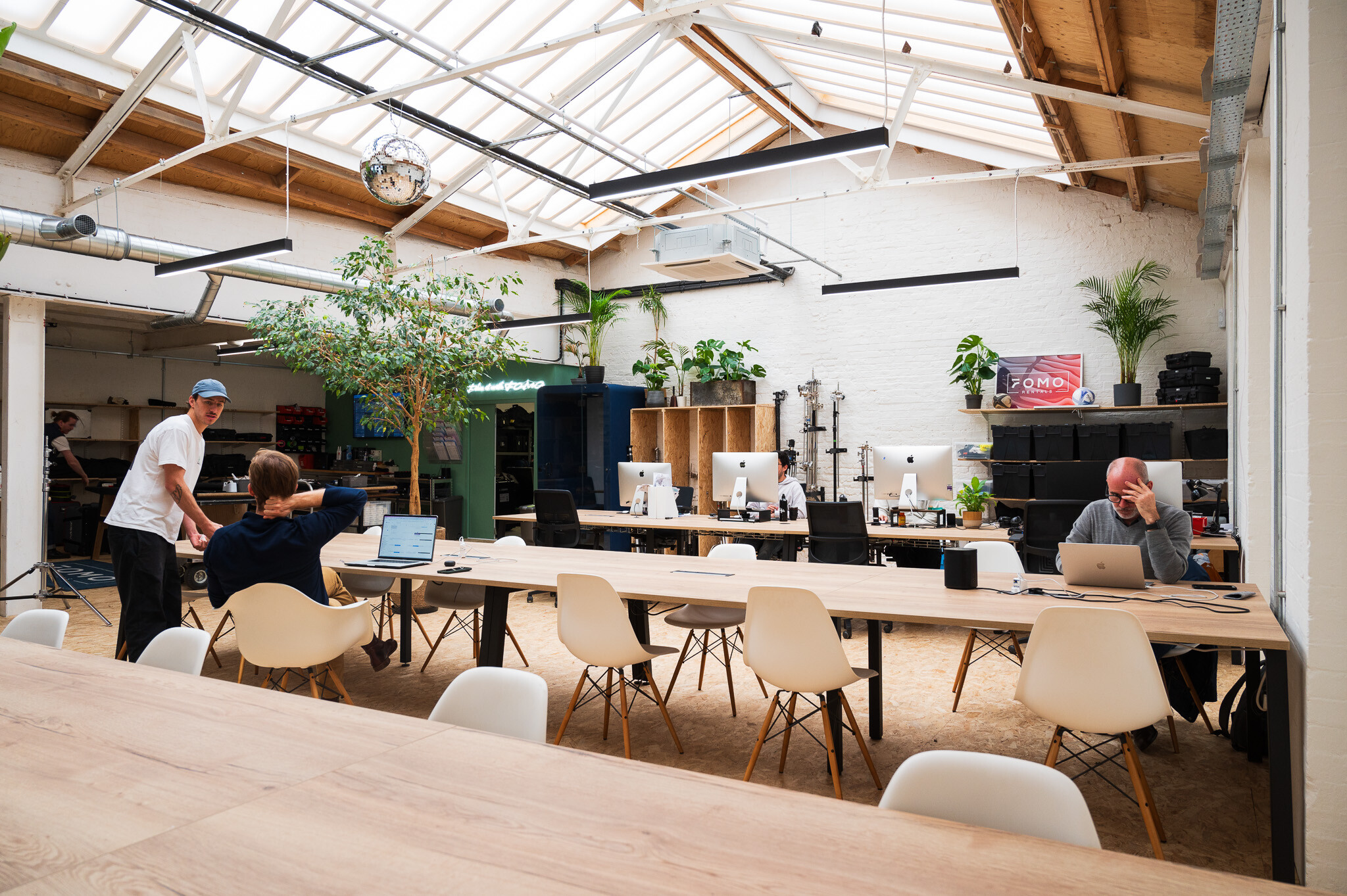 A workspace designed by Two, with a combination of private focus booths, shared desks, and lush greenery for a balanced office environment.