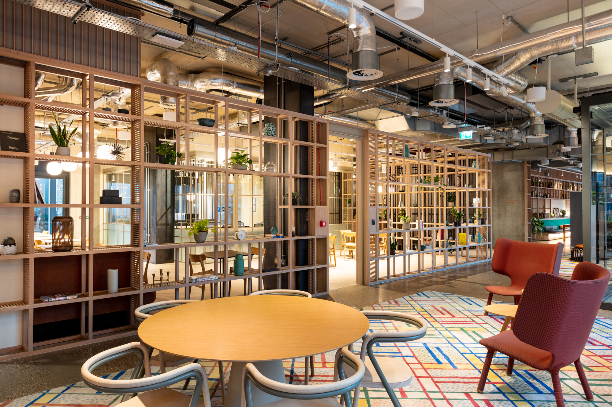 An open-plan breakout space at FORA Borough Market, created by Two, features wooden shelving, open-plan seating, and an inviting office atmosphere.