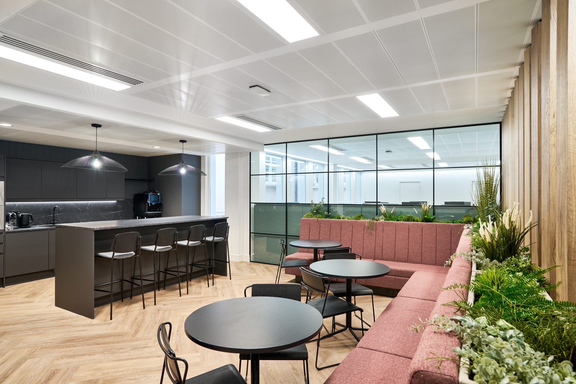 The redesigned teapoint at Gemserv’s workspace features full-height glazing, timber slats, and built-in banquette seating, creating a modern yet cohesive design by Two.