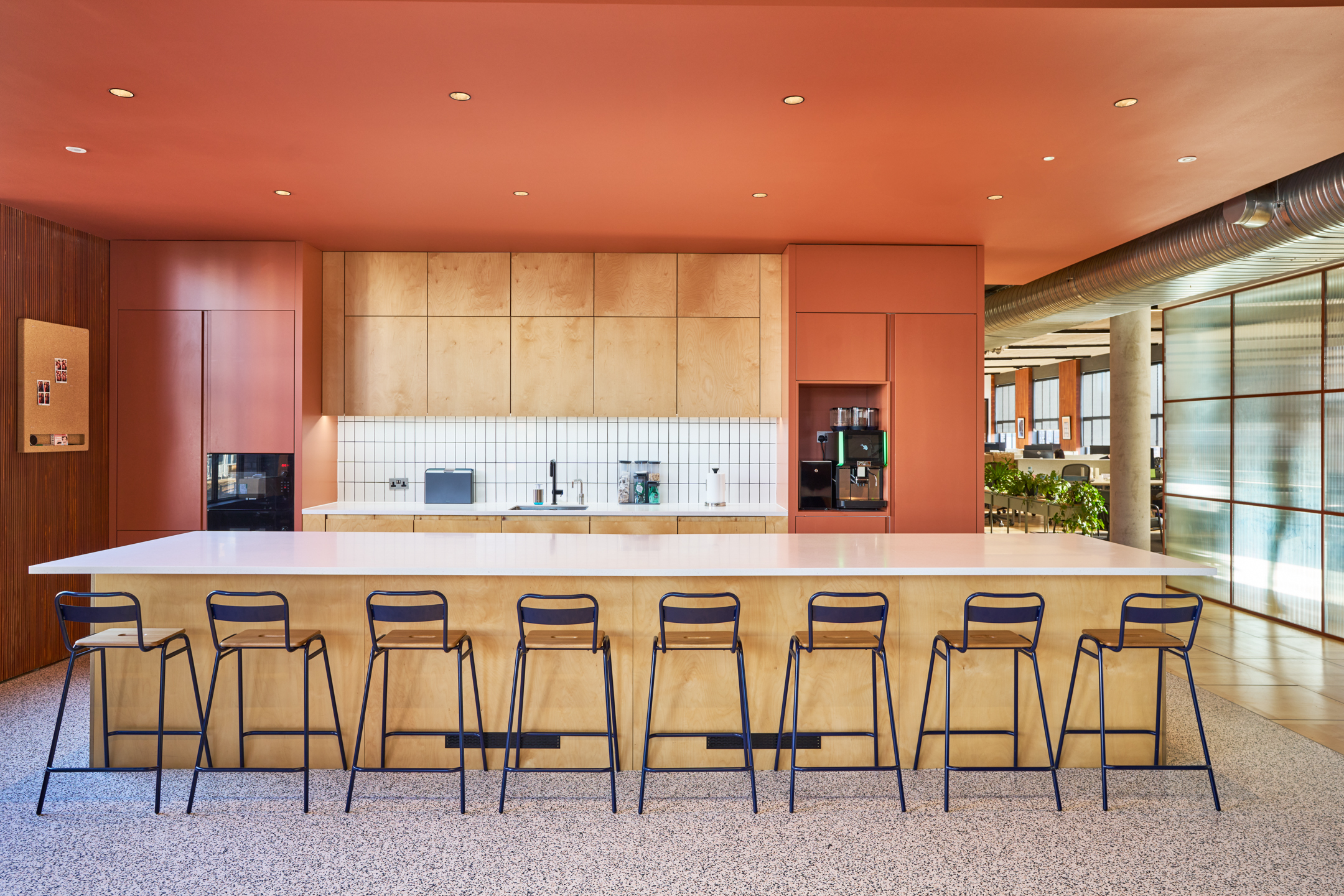 Vibrant teapoint area with modern wooden cabinetry and a central island for informal meetings.