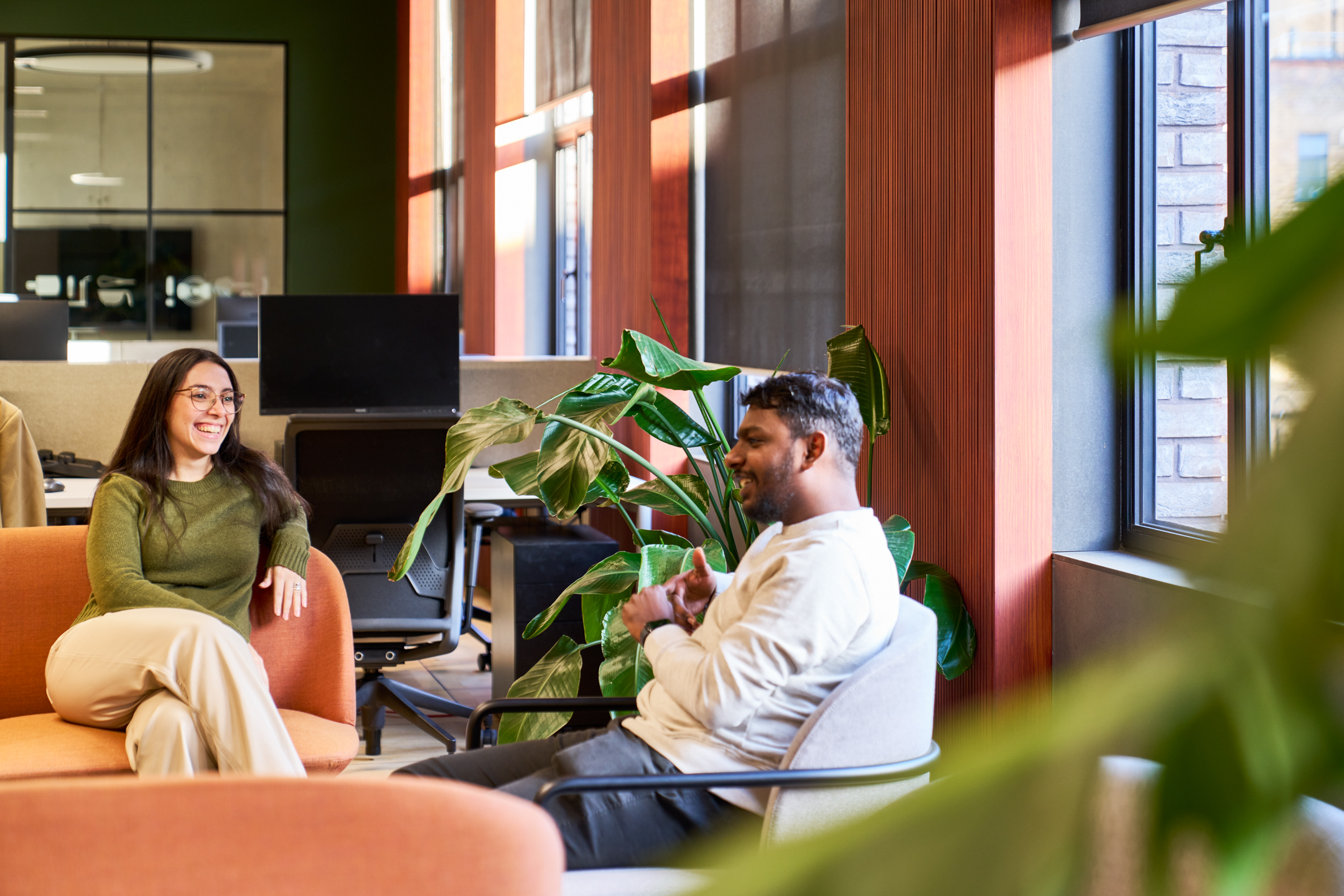 Colleagues enjoying a conversation in a breakout area with bright interiors and natural elements.