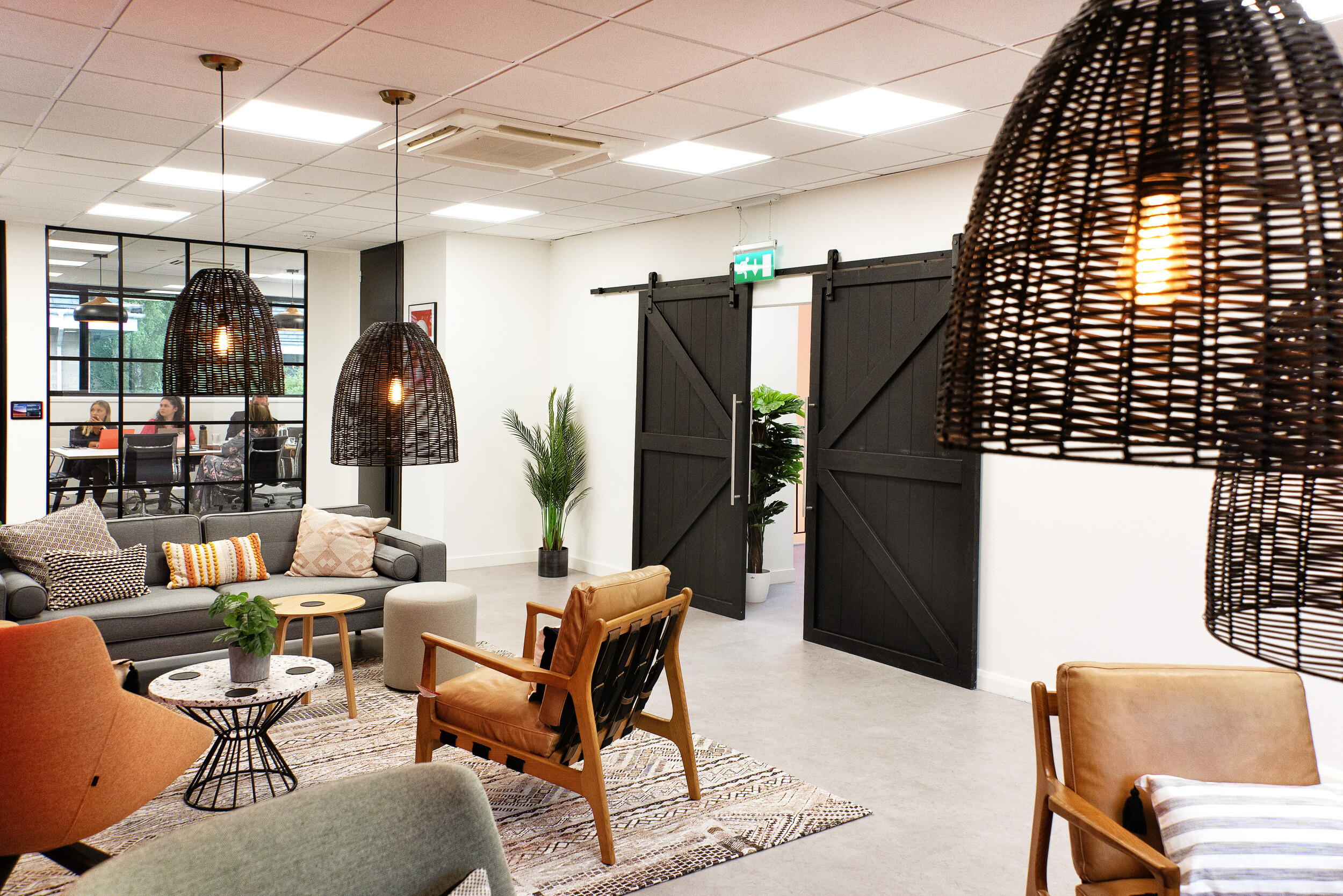 Bright and collaborative breakout area in the Koin office, designed by Two, with sliding barn doors, statement lighting, and stylish seating arrangements.