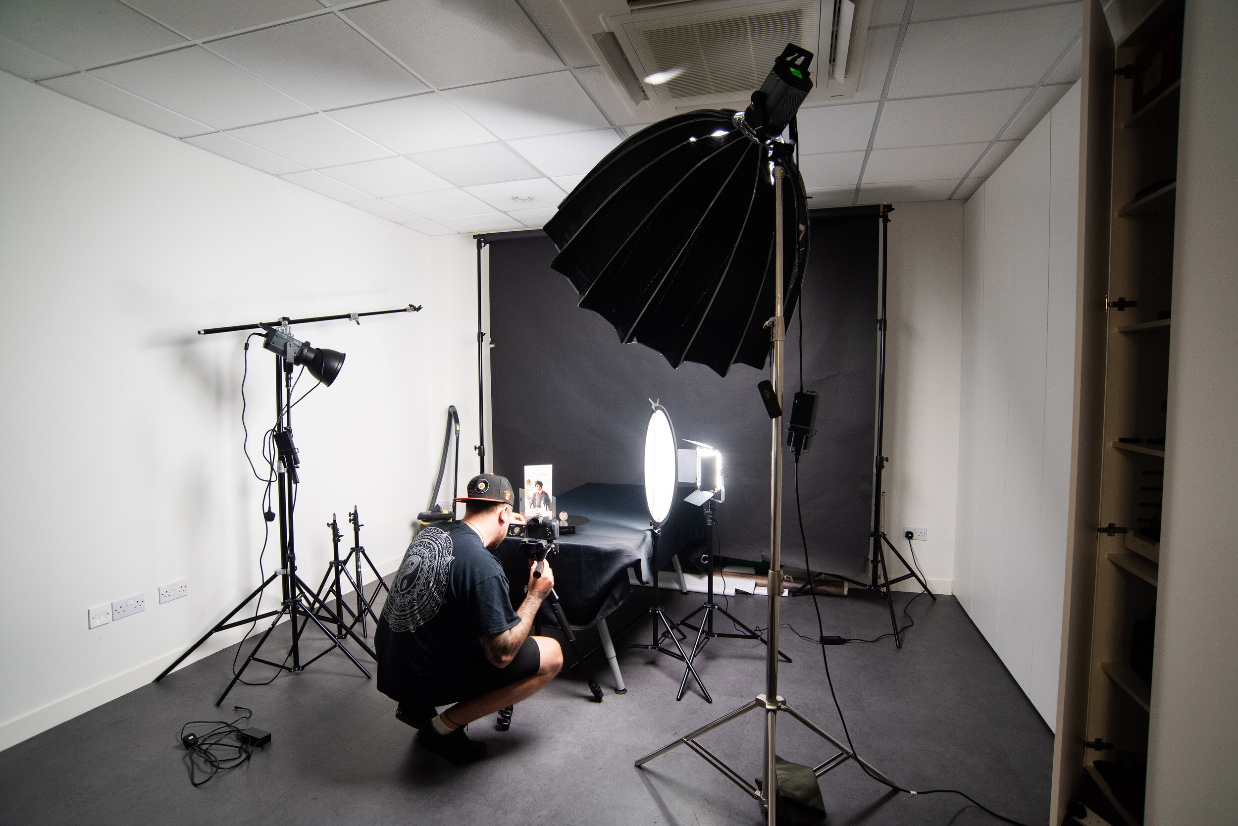 Photography studio equipped with professional lighting, black backdrops, and camera equipment for creative projects.