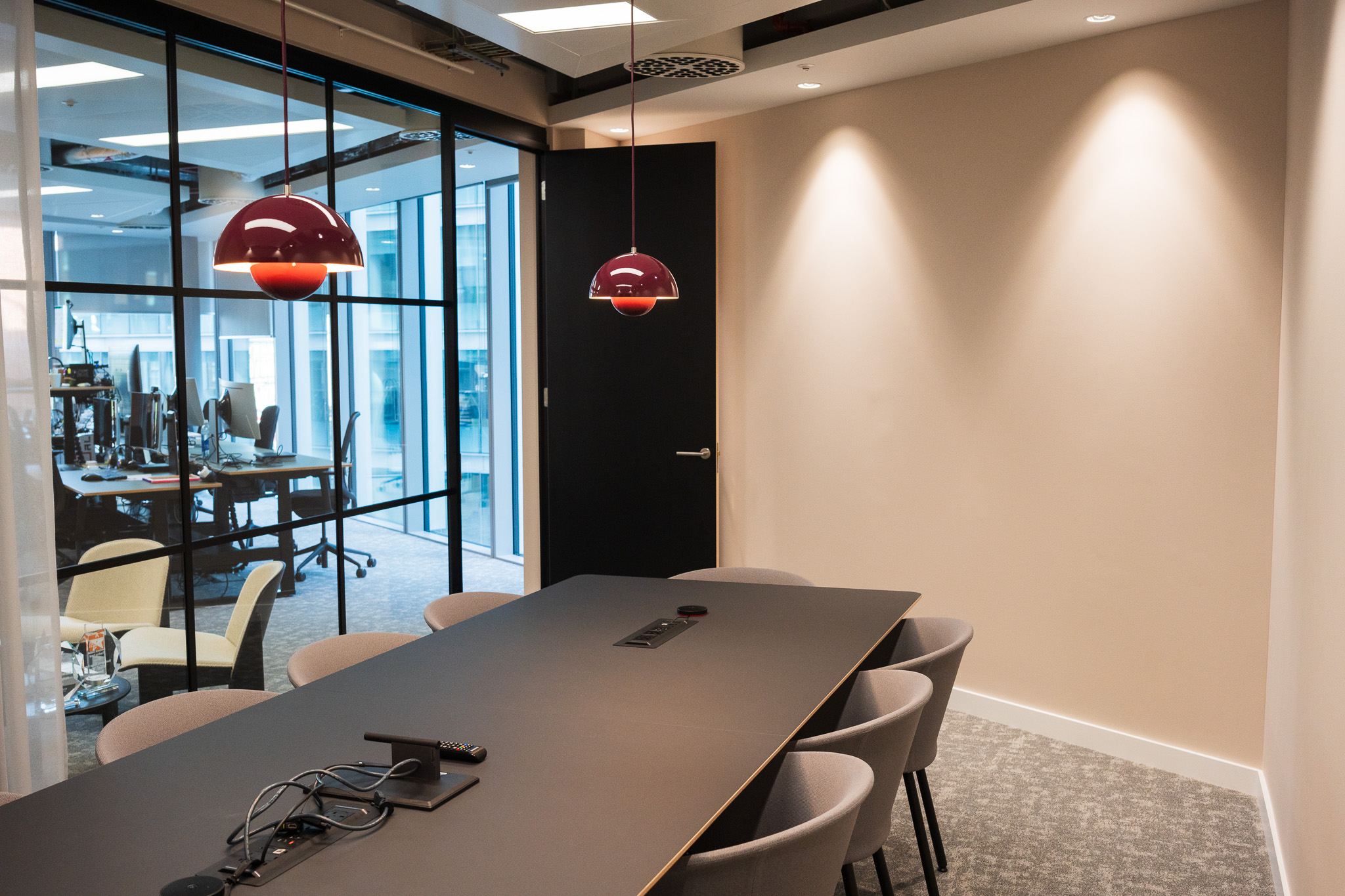 Contemporary meeting area in Landsec Nova North office, styled by Two with unique red pendant lighting and a multimedia setup.