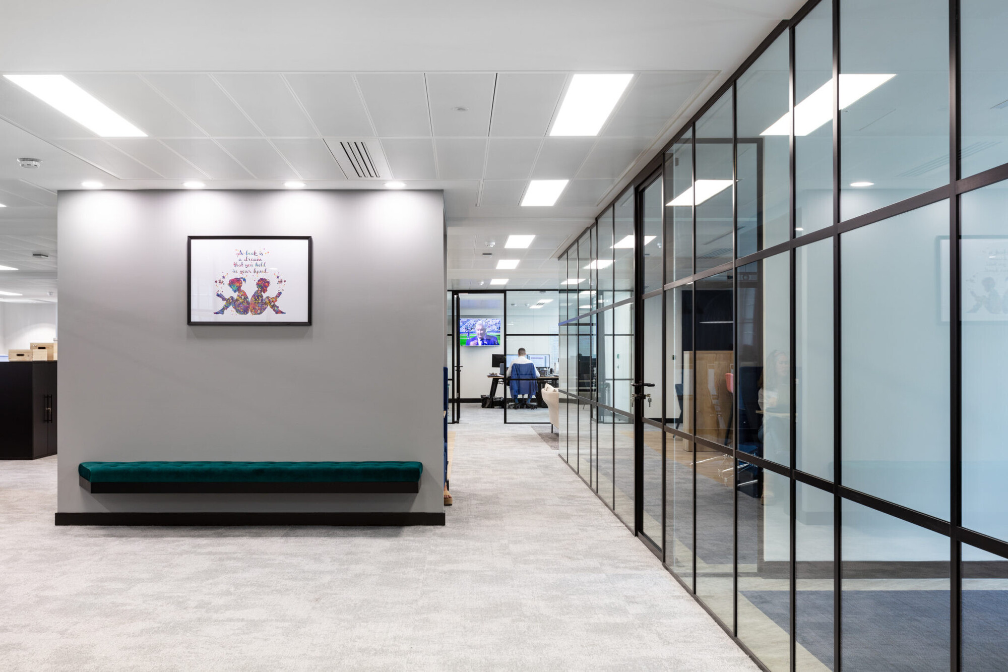 A hallway with glazing partitions leading to Literacy Capital's private offices, designed to balance transparency and privacy.