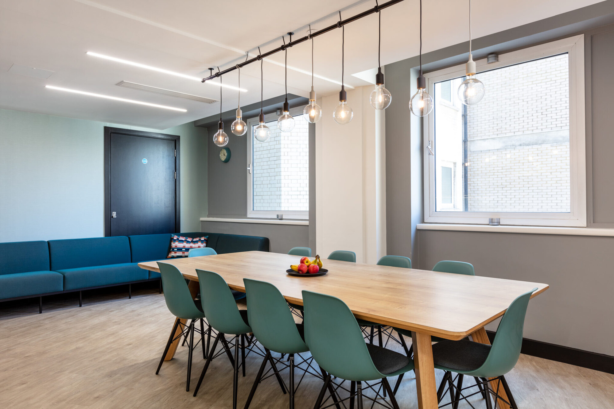 A dining area in the teapoint with a large wooden table and hanging pendant lights, offering a relaxed setting for Bookmark and Literacy Capital.