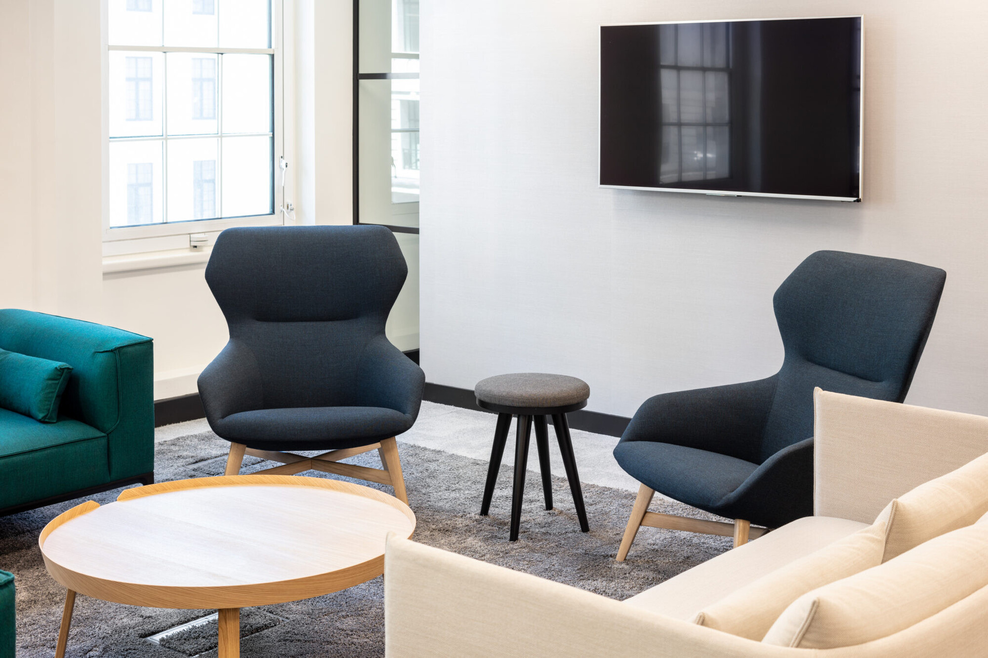 A close-up of the breakout area, featuring modern armchairs and a TV, designed for informal meetings and relaxation.