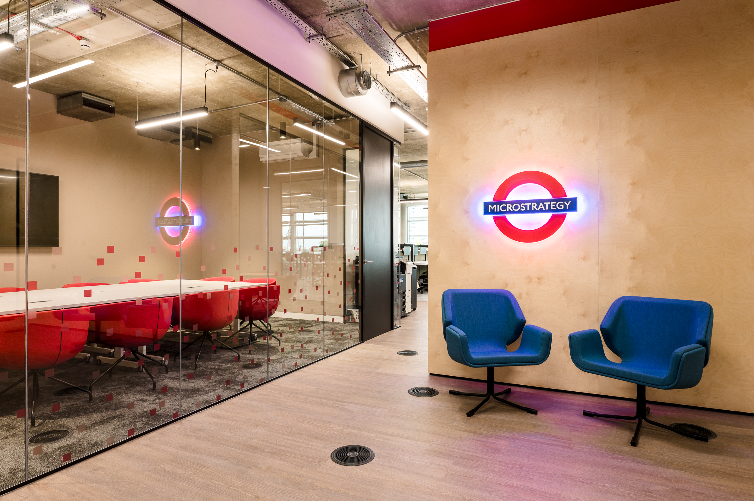 MicroStrategy’s collaborative office space designed by Two, showcasing a bold meeting room with glass walls with bespoke manifestation and iconic red furniture.