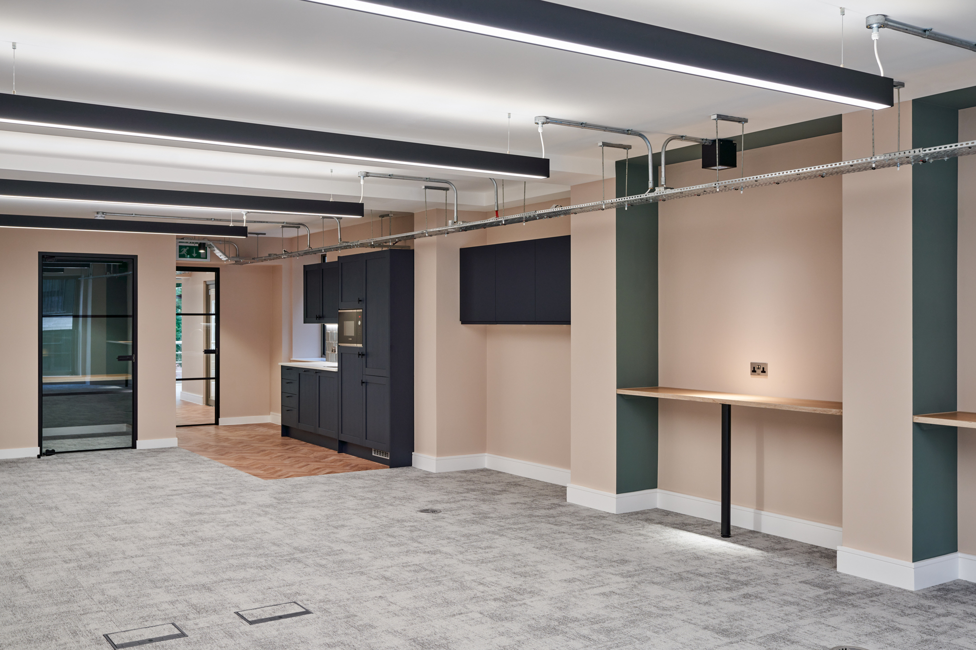 Open workspace in the Nolan Partners office featuring built-in desks and a kitchen area, delivered by Two.