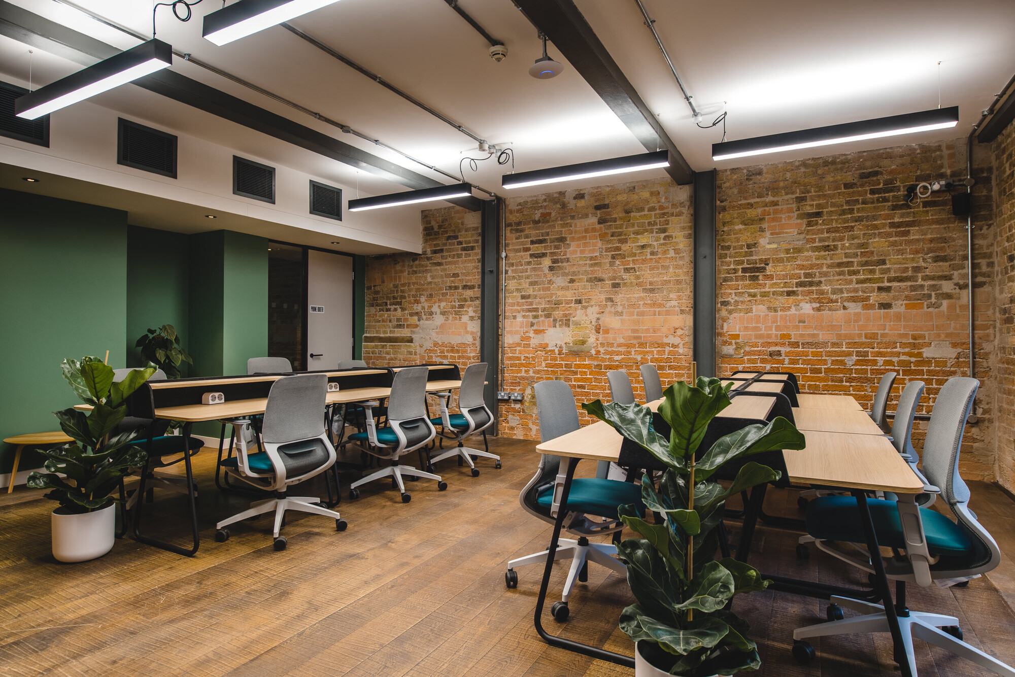 Patch co-working area designed by Two, showcasing a relaxed seating space and communal tables under exposed wooden beams.