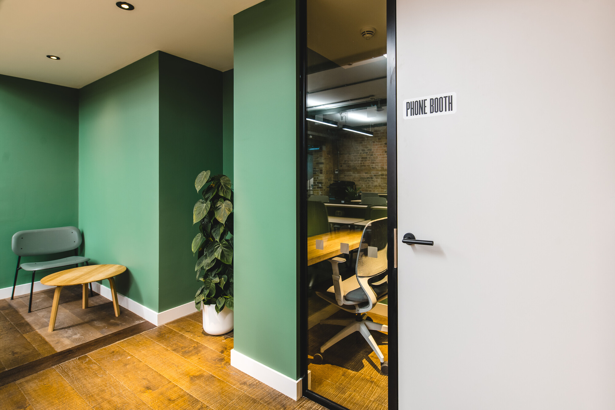 Private phone booth and breakout area at Patch by Two, featuring green walls, wooden floors, and modern furnishings for a calm workspace