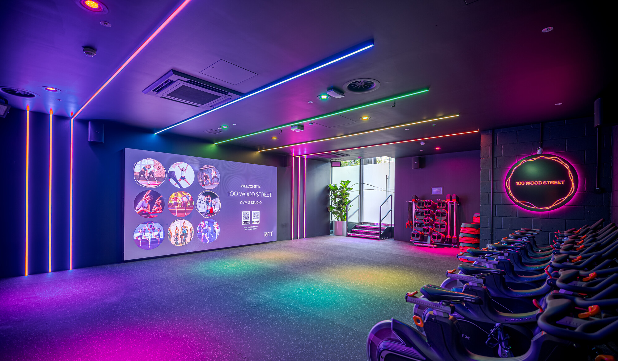 ReFIT Gym at 100 Wood Street showcases vibrant dynamic lighting and a large LED display, designed by Two to enhance the immersive fitness experience