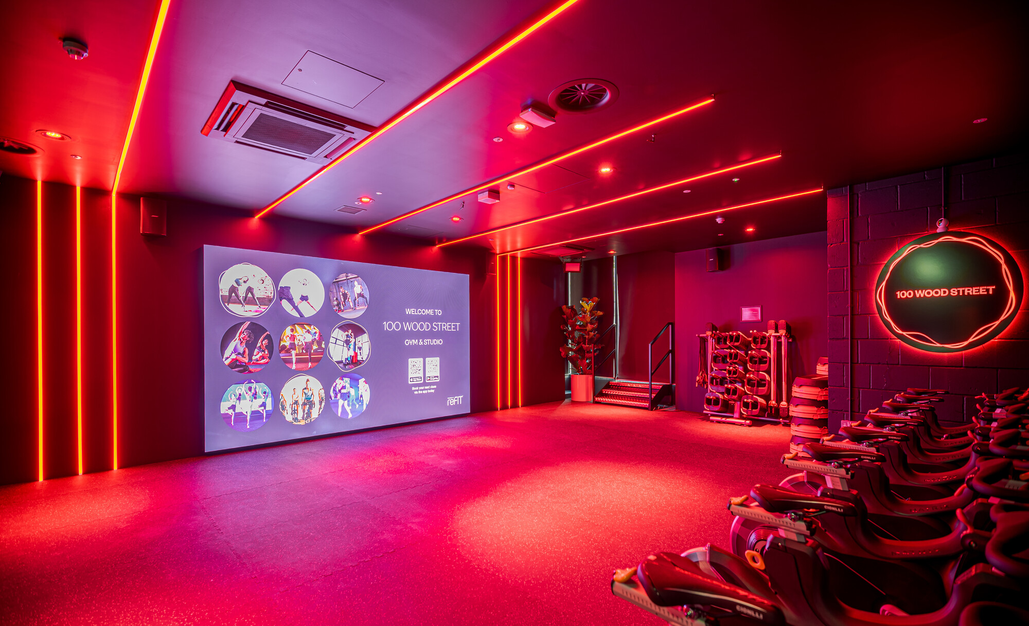 Dynamic lighting in the ReFIT Gym's cycling studio creates an immersive workout environment, featuring advanced technology and sleek interior design by Two.