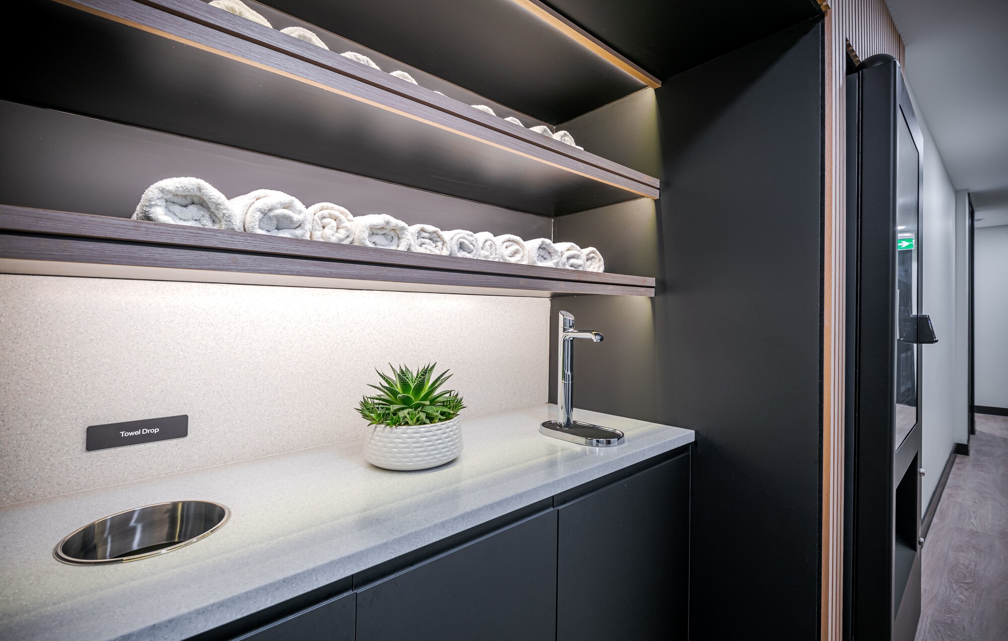 Modern towel station at ReFIT Gym, 100 Wood Street, featuring a polished countertop, integrated towel drop, and neatly organised shelves.