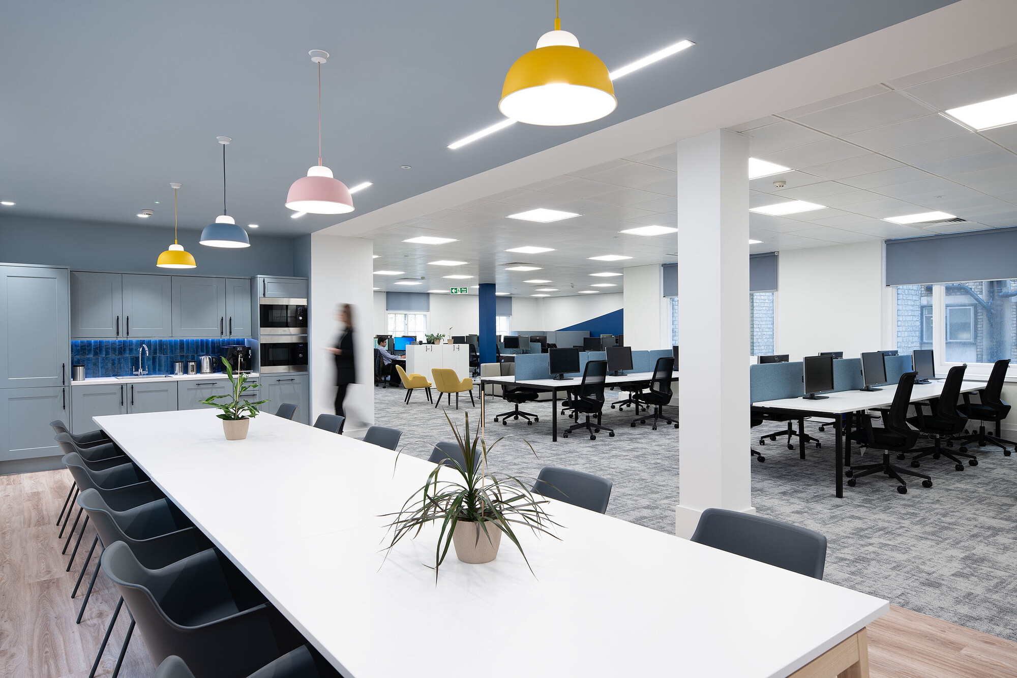 Open collaborative space at Socotec with mustard yellow lights, plants and seats.