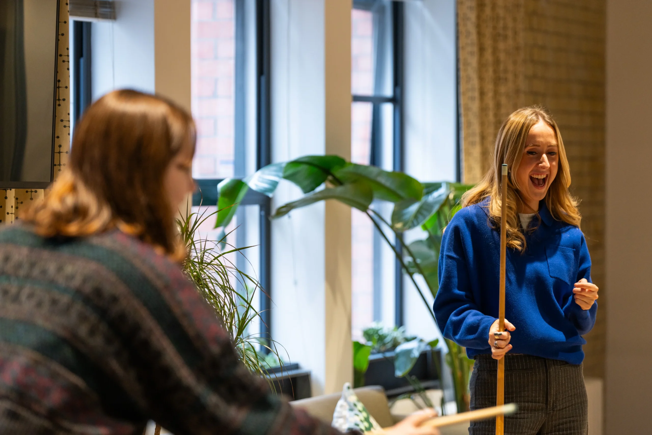 Team members at Two play pool in the office on a break