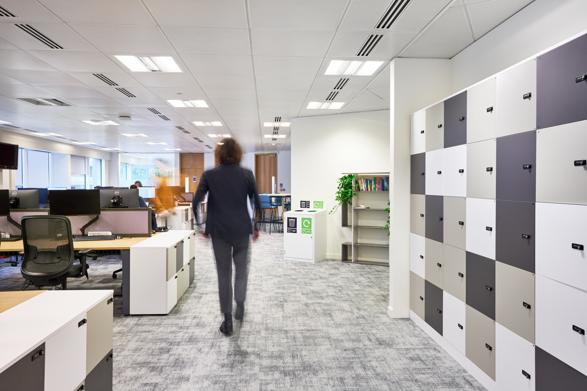 Open office space at Tech UK with locker space, rows of desks, and people walking through.