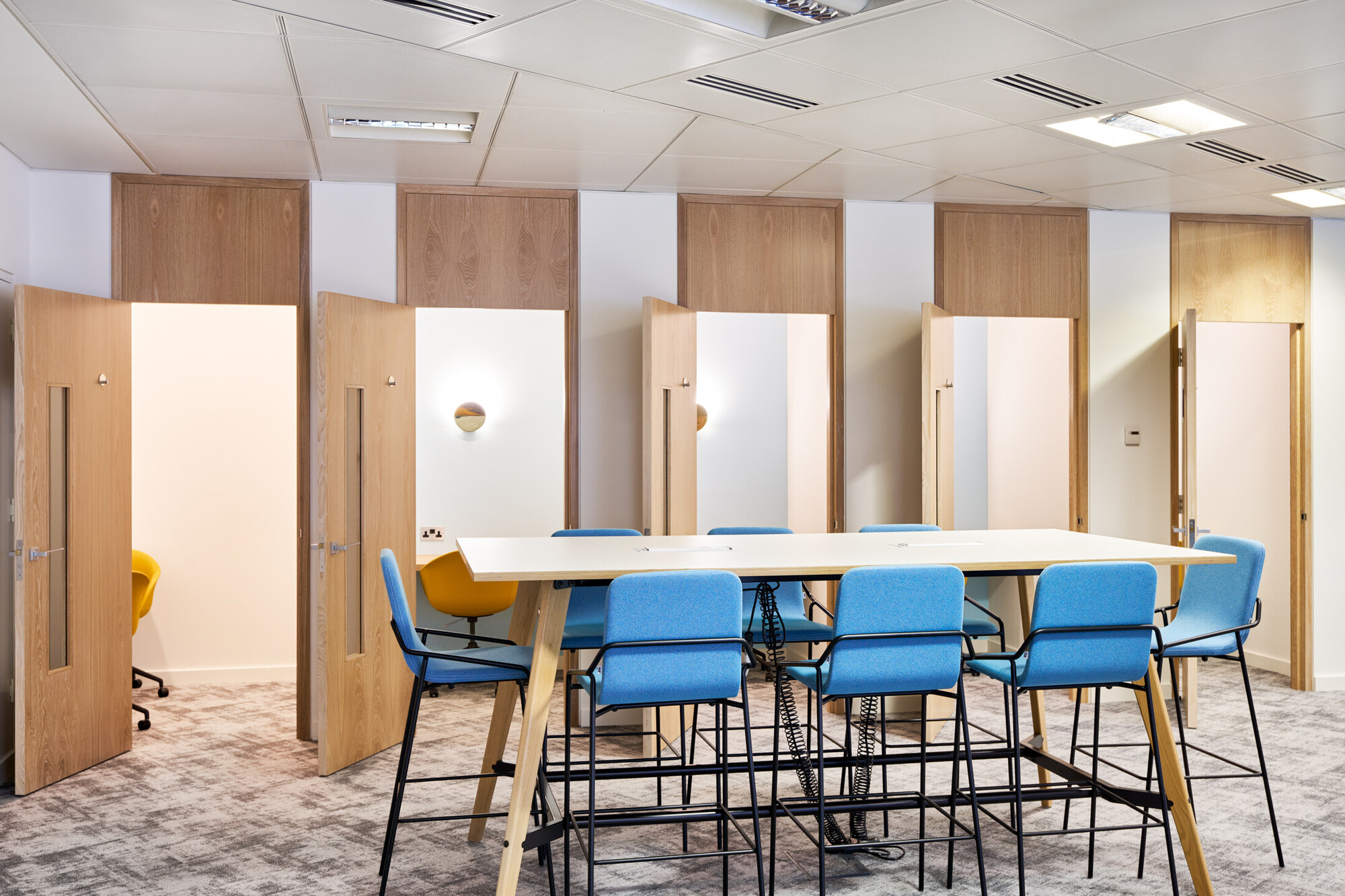 Phonebooth and breakout area at Tech UK, with an island featuring blue high stools