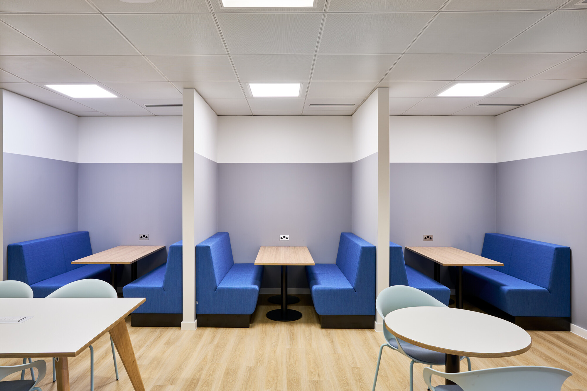 Seating area at Tech UK with blue opposing chairs and desks