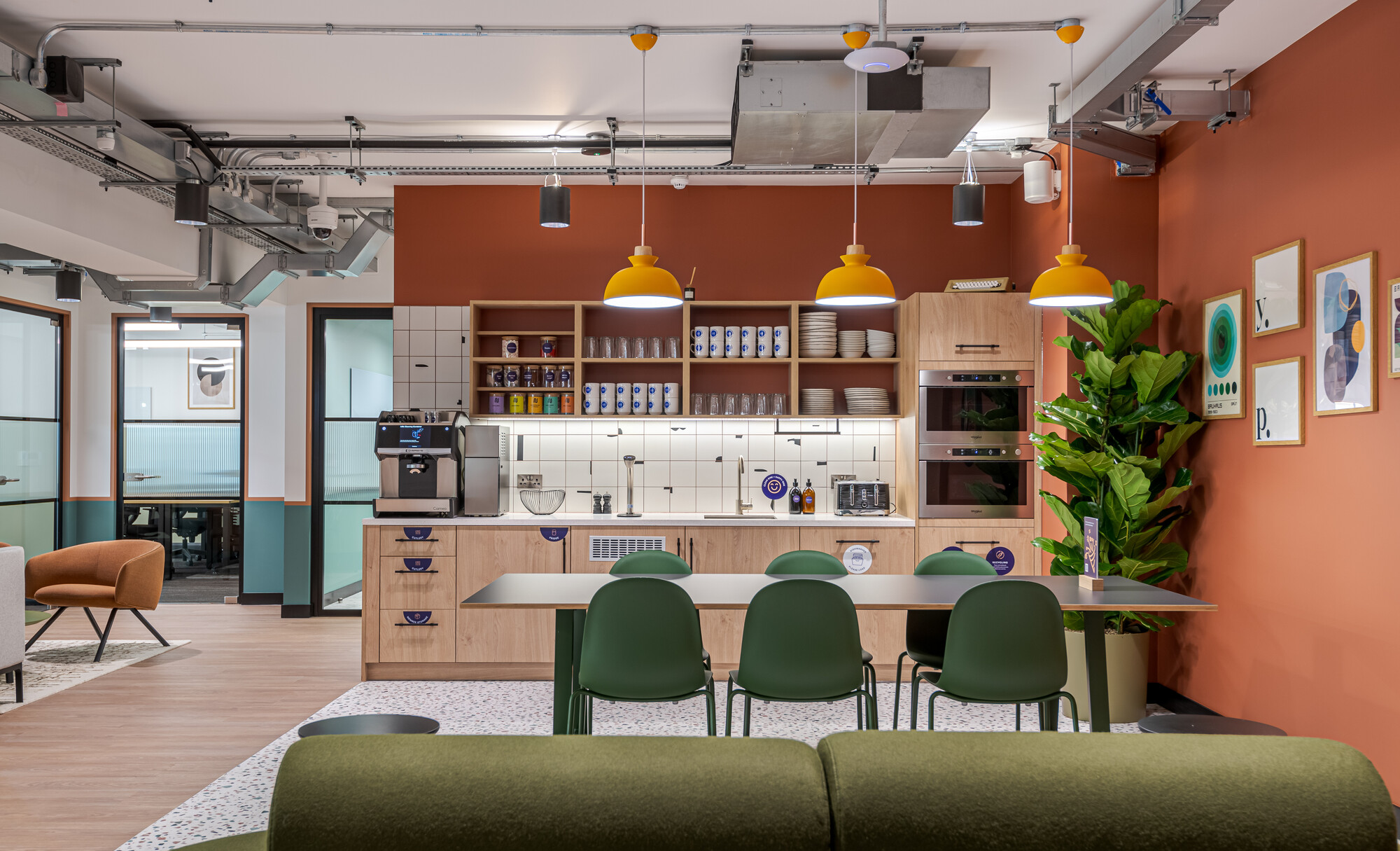 Teapoint area at the Typewriter Building featuring bold orange walls, open shelving, and communal seating, designed by Two for Work.Life.