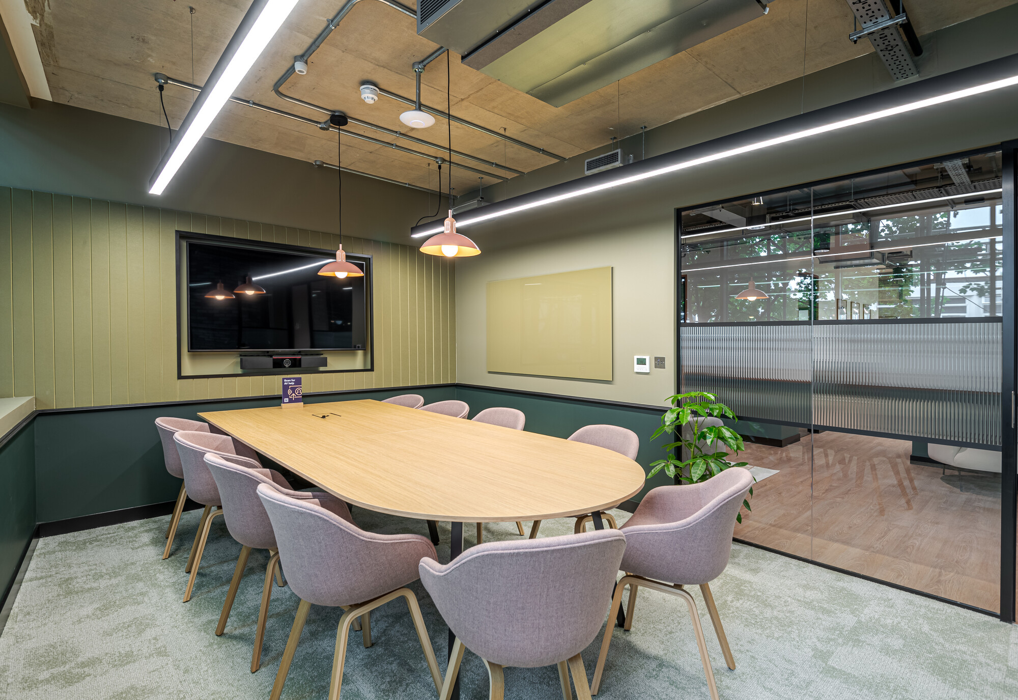 Modern meeting room at the Typewriter Building with soft pastel chairs, a wooden table, and olive-toned walls, designed by Two for Work.Life.