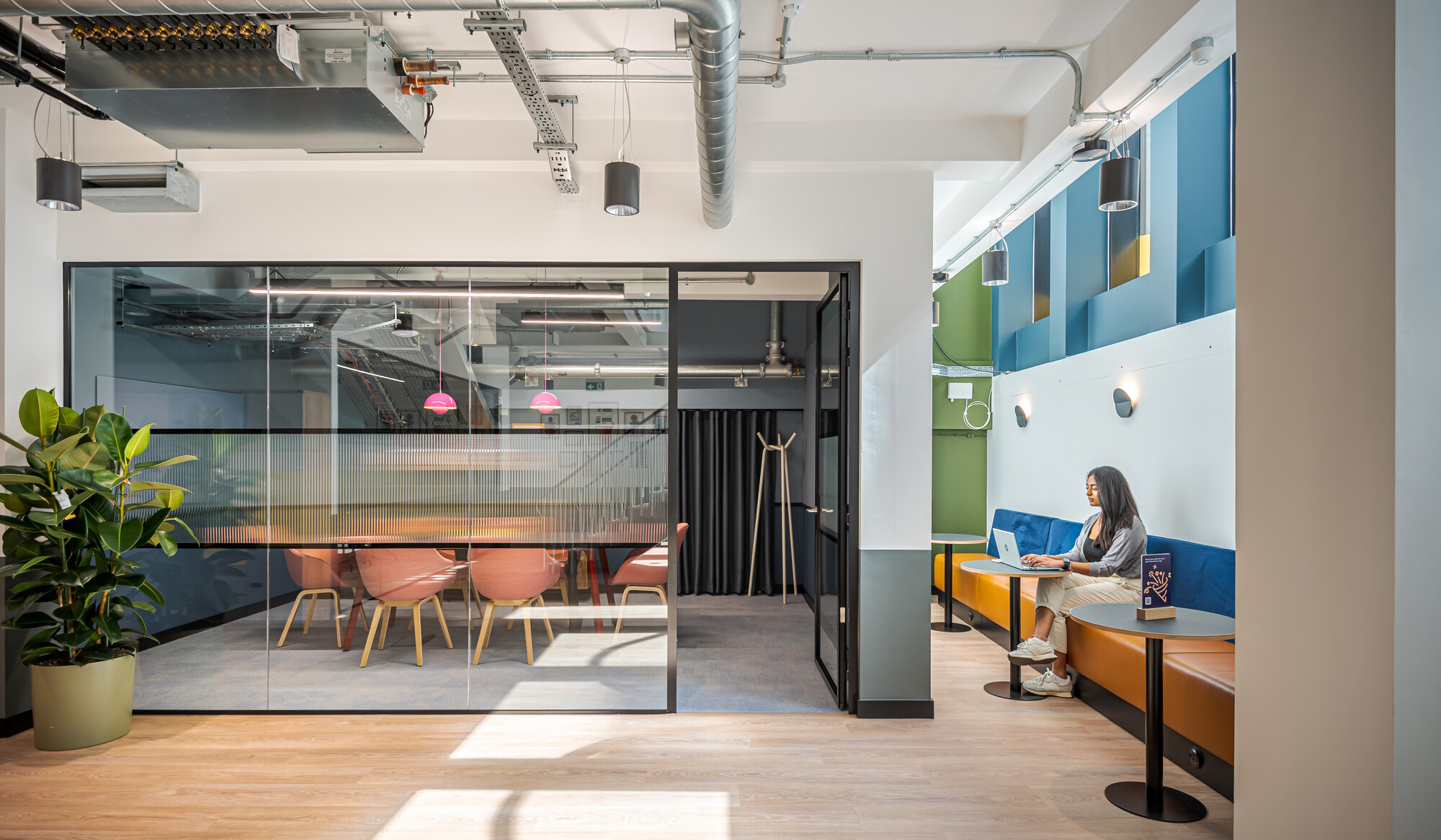 Collaborative area at the Typewriter Building with glass-walled meeting rooms and vibrant seating, designed by Two for Work.Life.