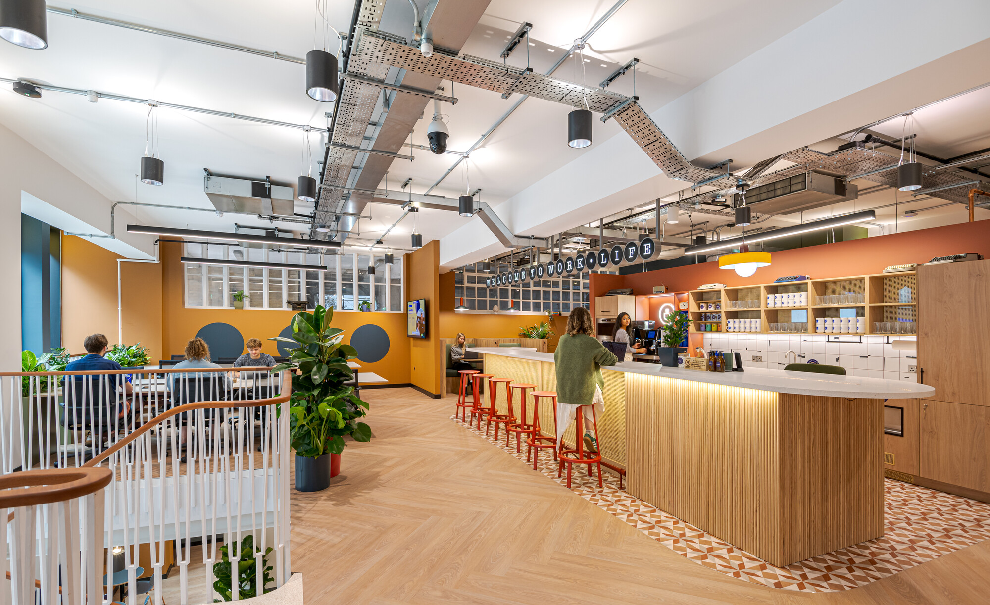 Welcoming reception and bar area at the Typewriter Building, featuring bold colours and rattan accents, designed by Two for Work.Life.