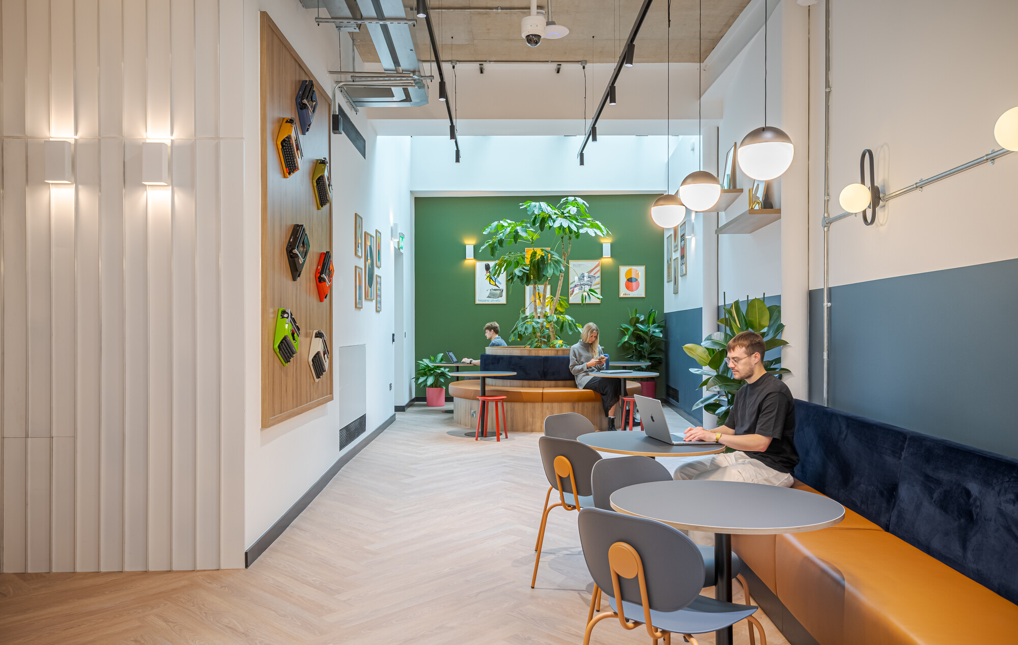 The winter garden at the Typewriter Building, featuring bespoke seating, vibrant greenery, and retro typewriter wall decor, designed by Two for Work.Life.