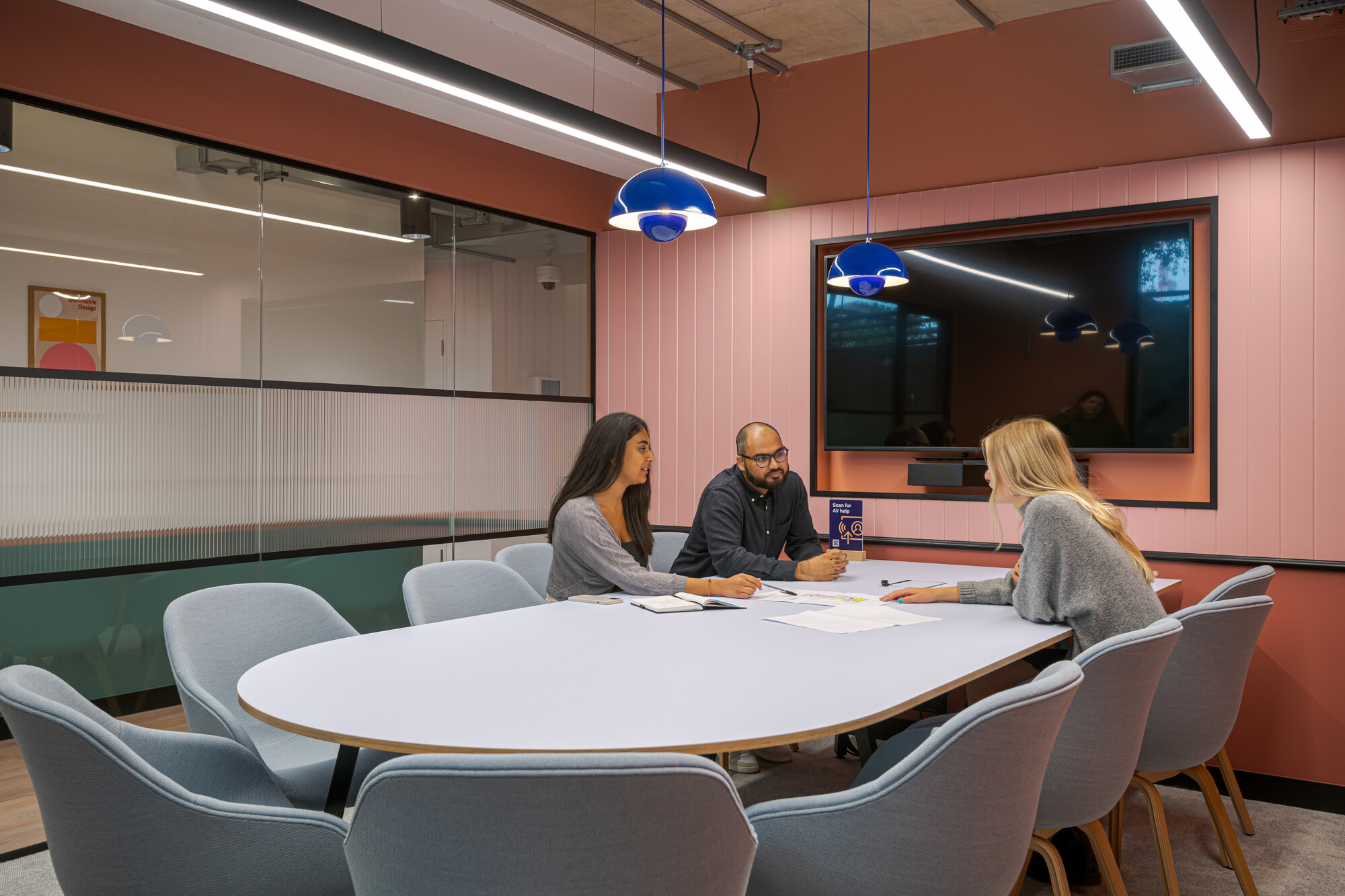 A collaborative meeting room at the Typewriter Building, designed by Two for Work.Life, showcasing a pink panelled wall, blue pendant lights, and modern furnishings.