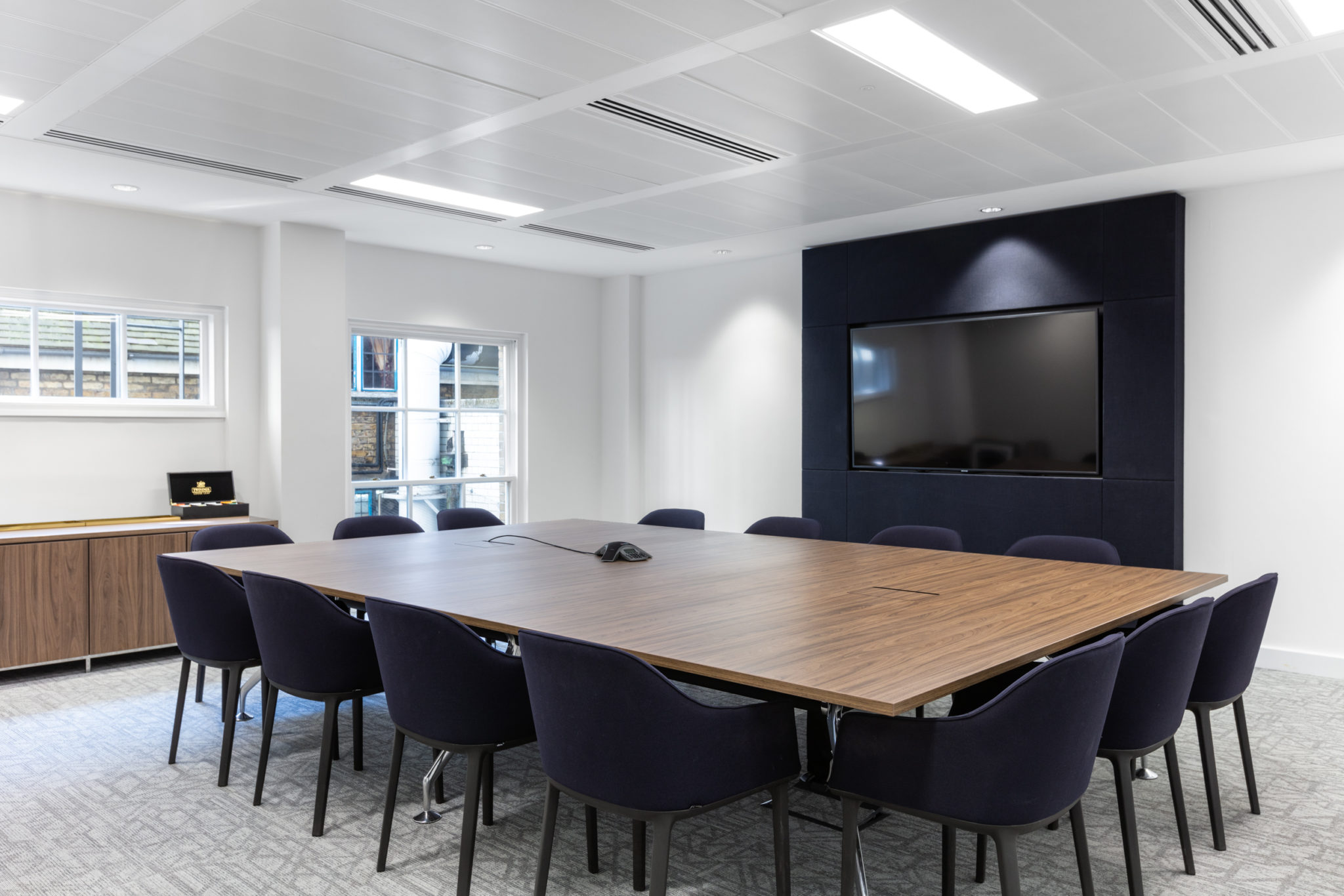 Boardroom at Urban Exposure workspace designed by Two, complete with a large wooden table, navy chairs, and a high-tech screen for seamless meetings.