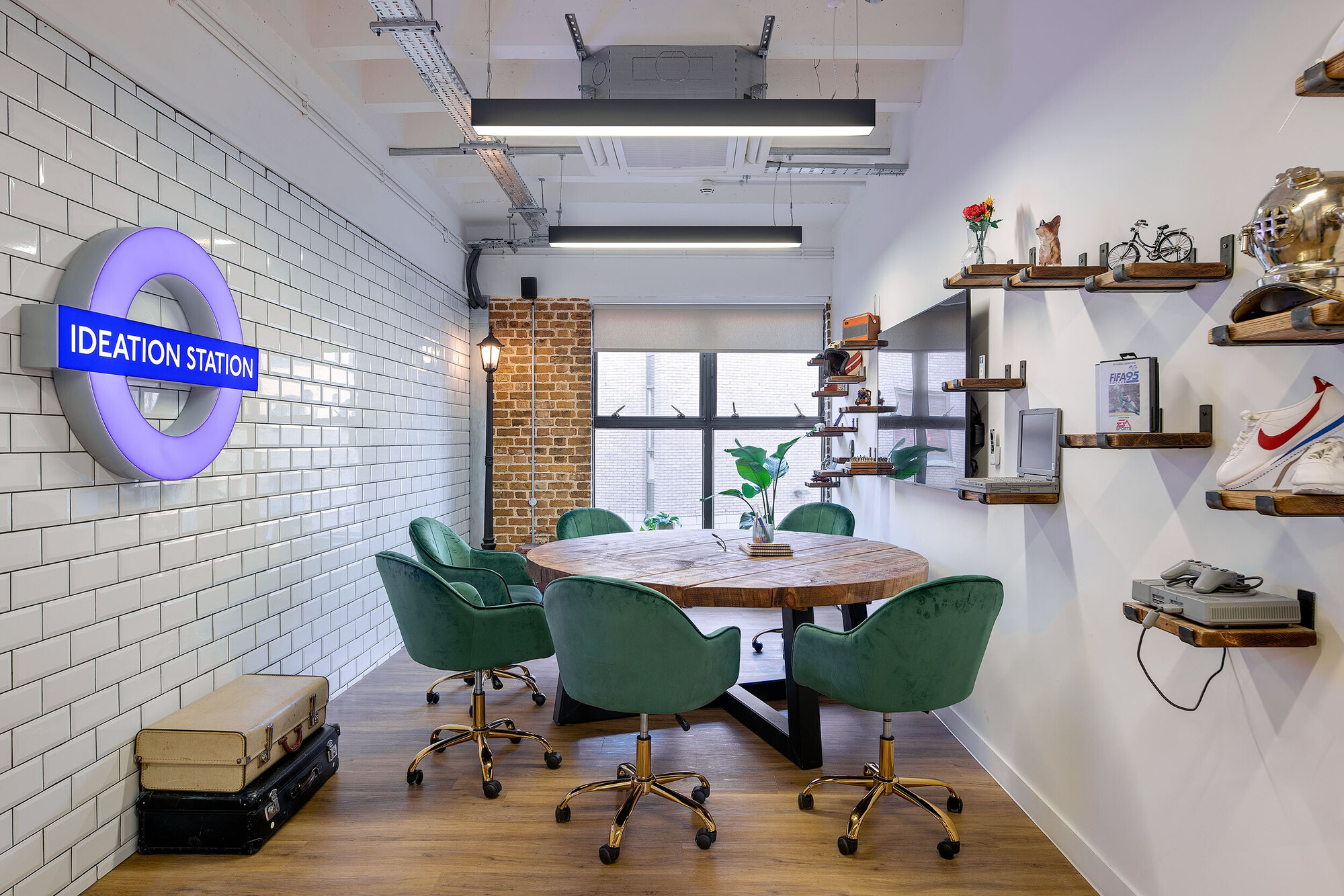 The Ideation Station at Wiser’s office, designed by Two, featuring green velvet chairs, a round wooden table, and unique shelving decor.