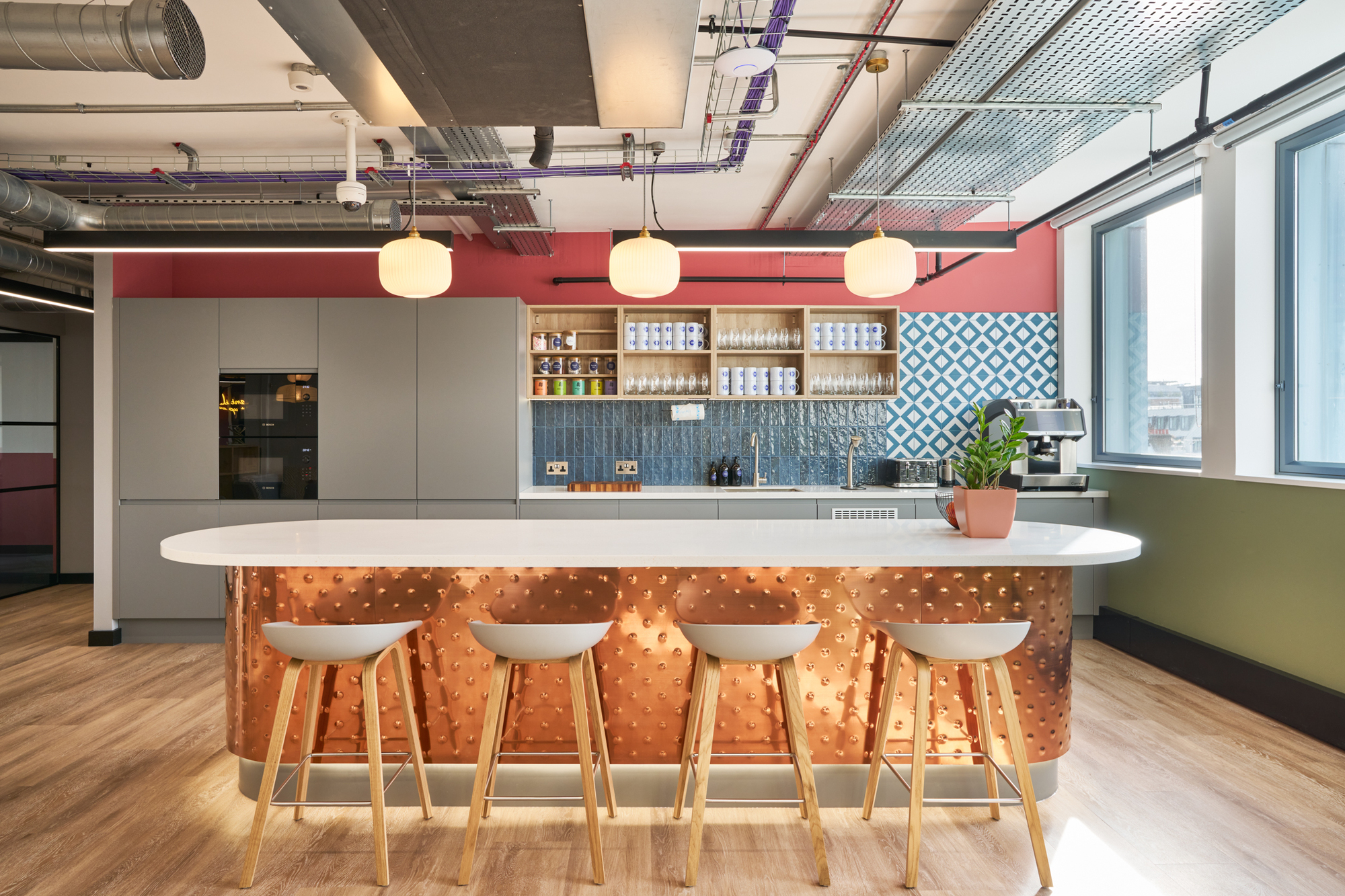 Stylish teapoint at Work.Life Waverly House by Two, featuring a textured copper island, bold tile backsplash, and ample natural light for a vibrant setting.