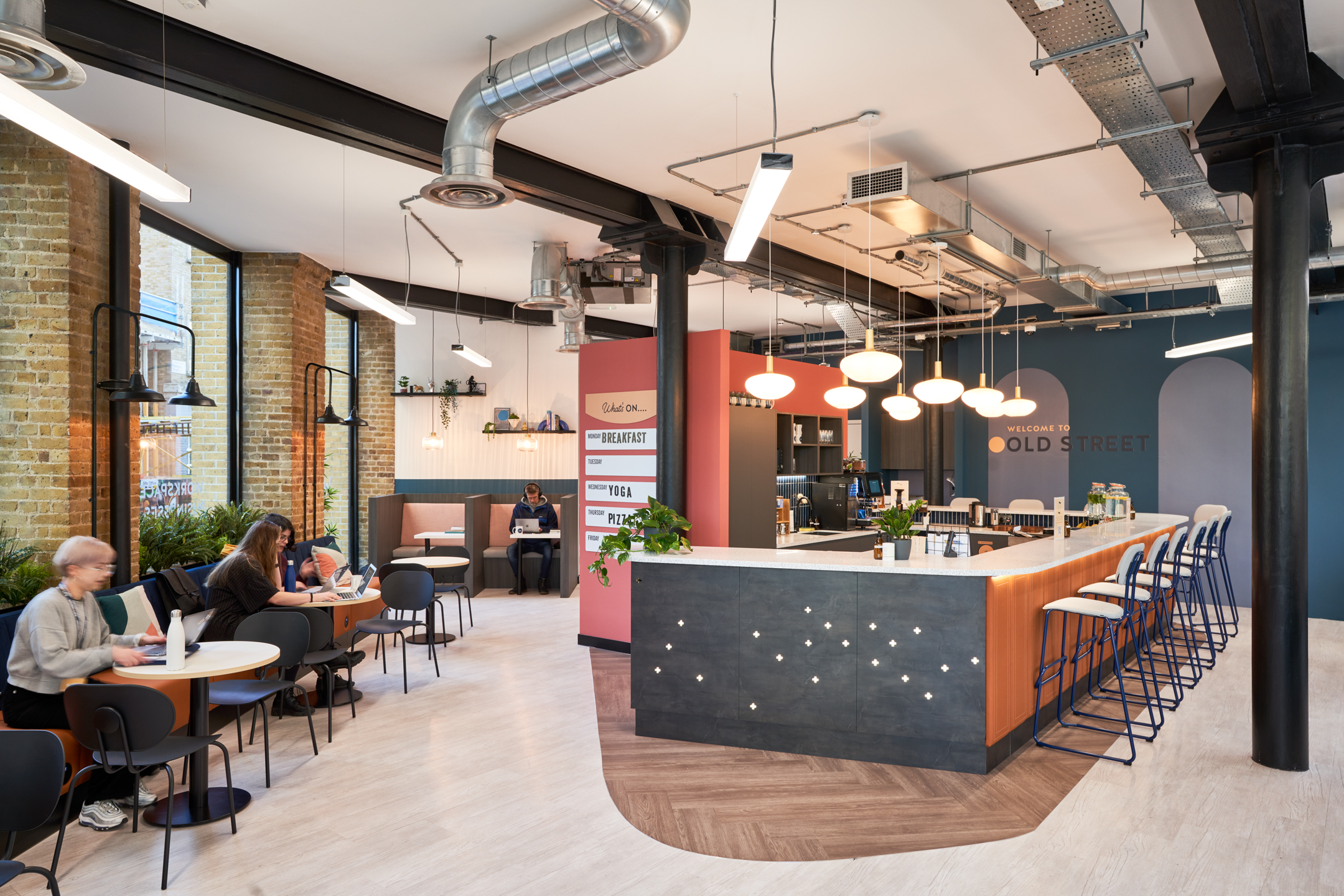 A vibrant communal area at Work.life Rivington House, designed by Two, featuring a modern bar, stylish seating, and natural light creating an inviting workspace for collaboration.