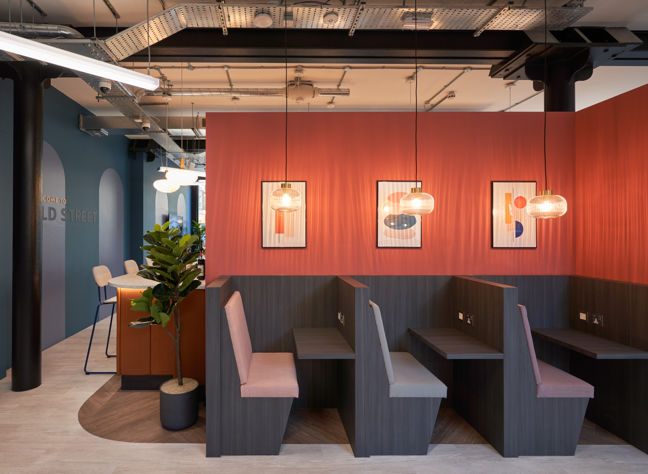 Private booth seating at Work.life Rivington House by Two, with warm orange accents and contemporary lighting, perfect for focused work in a stylish workspace.