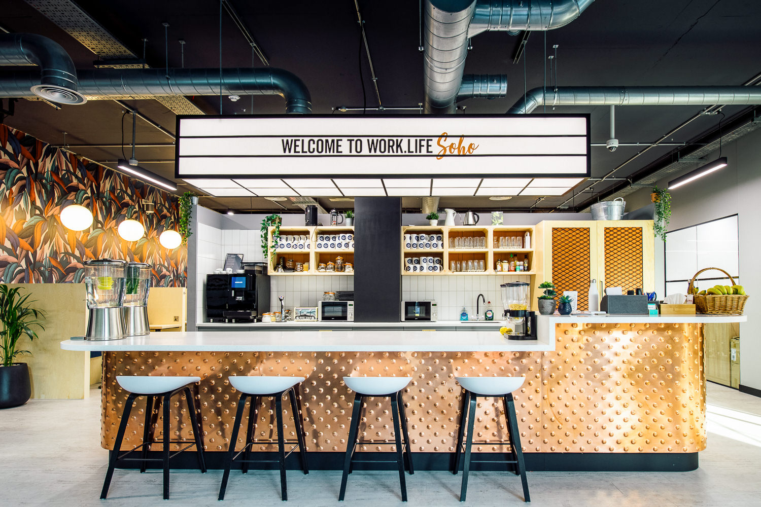 The vibrant kitchen area at Work.life Soho, designed by Two, featuring a stylish copper bar, open shelving, and inviting workspace seating.