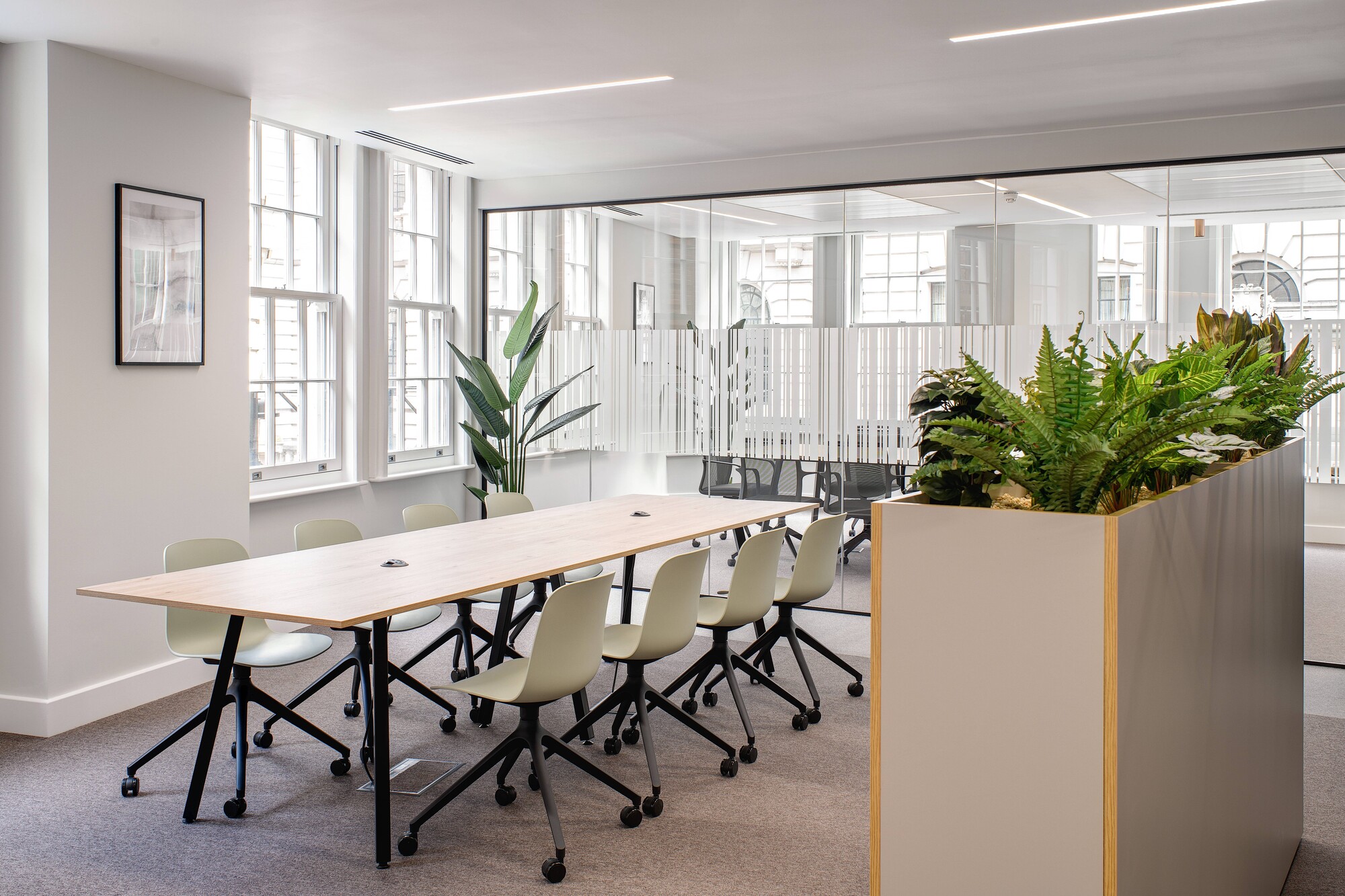 Tenant-Ready™ workspace by Two featuring a light-filled meeting area with modern furnishings and natural greenery dividers for a refreshing atmosphere.