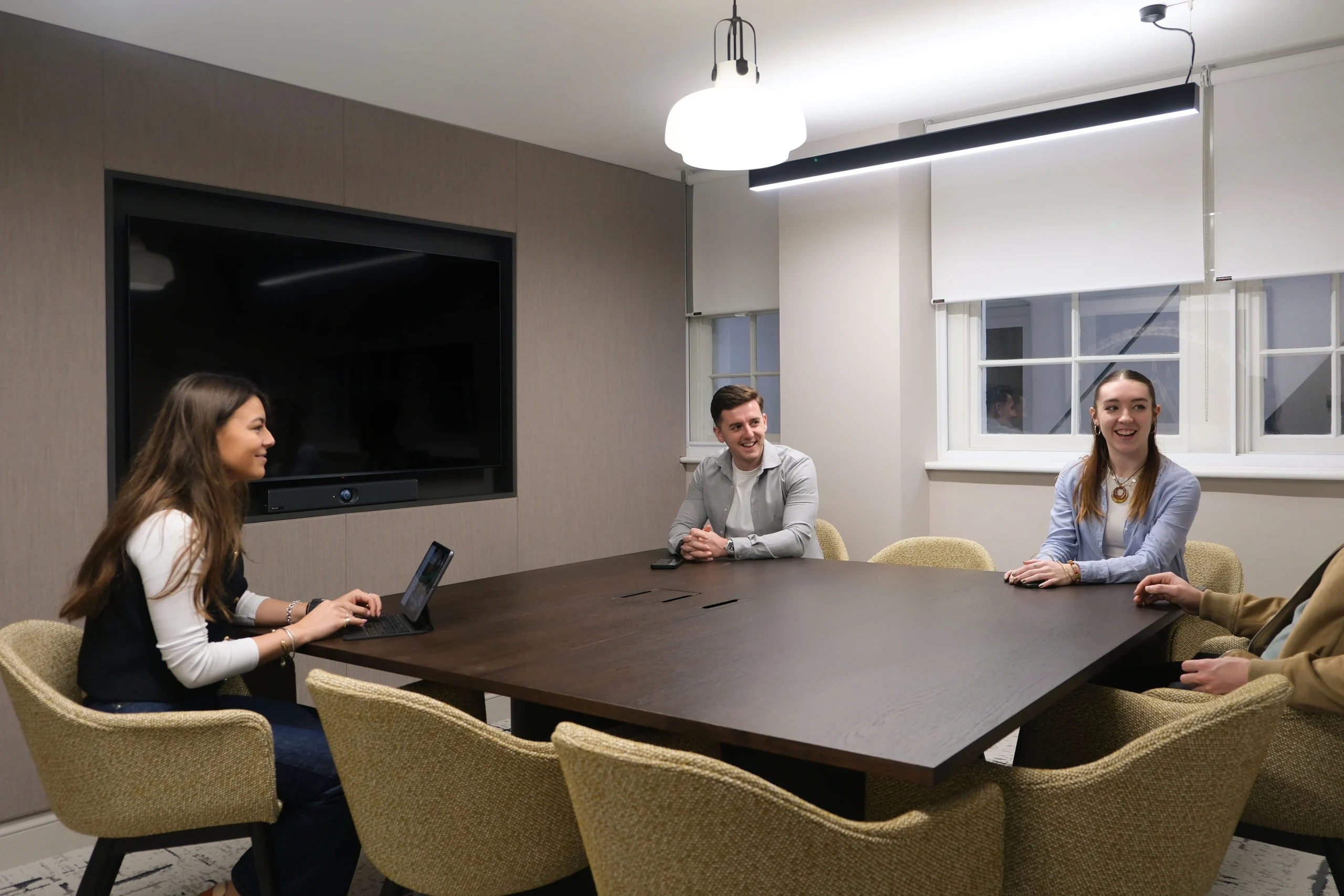 33 Mayfair meeting room with large oak table, and green seating, with a screen.