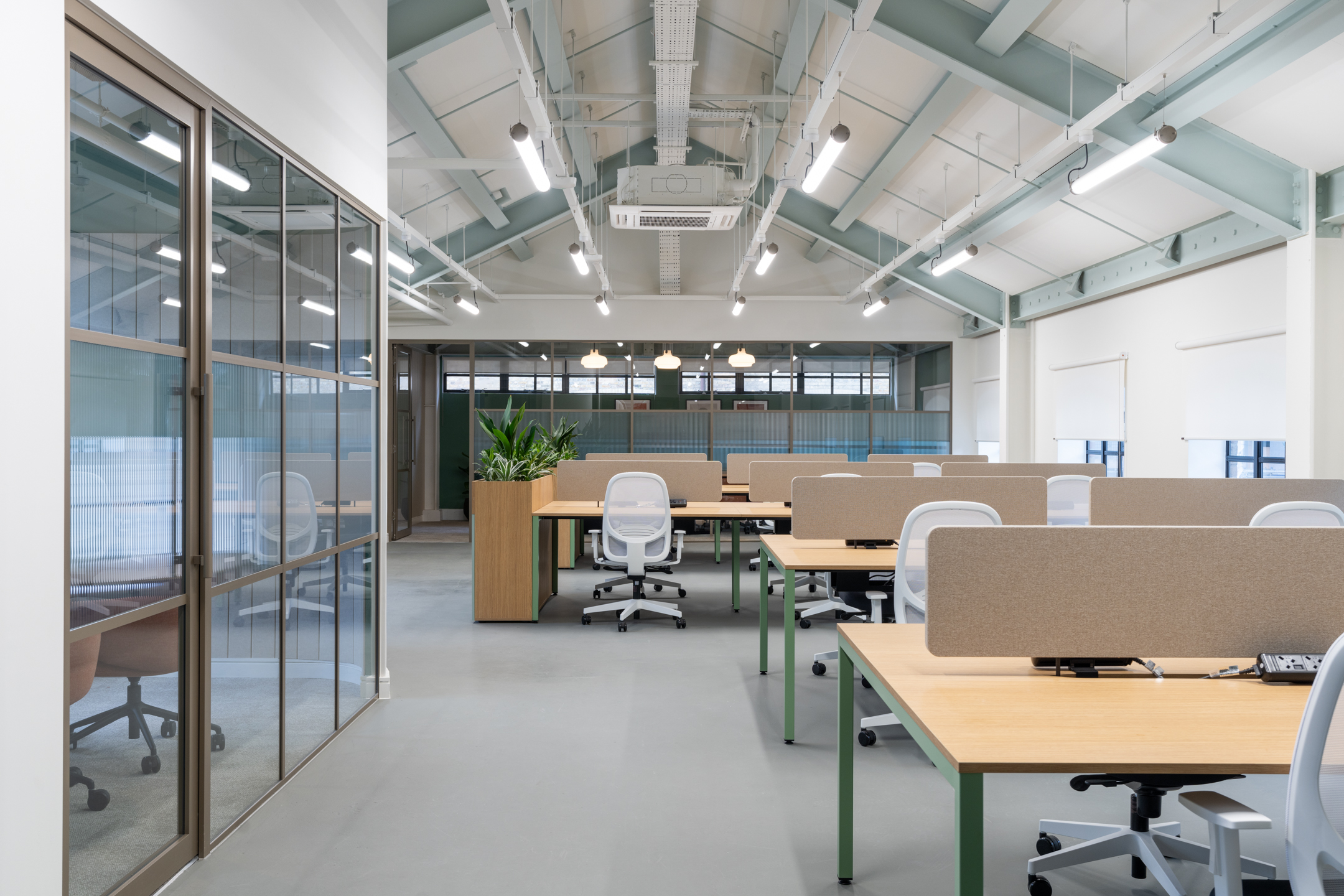 The Varnish Works open-plan workspace, with seating area, open white walls, and a glass meeting room.