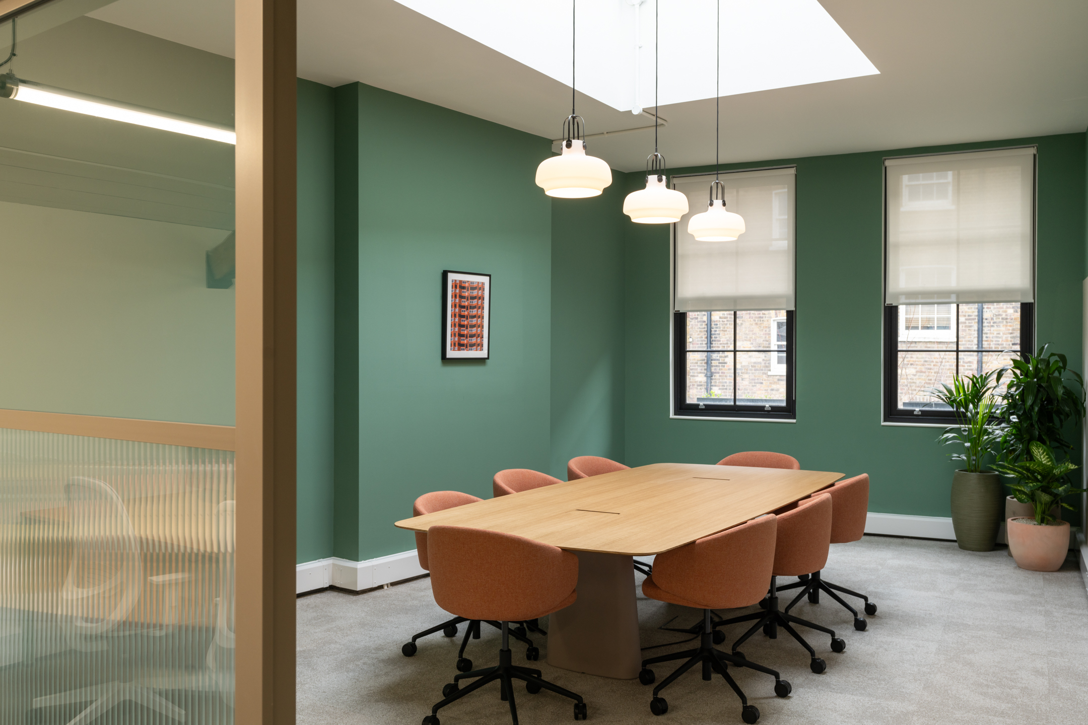 The Varnish Works meeting room, featuring sage green walls, hanging bespoke lighting and a large oak table.