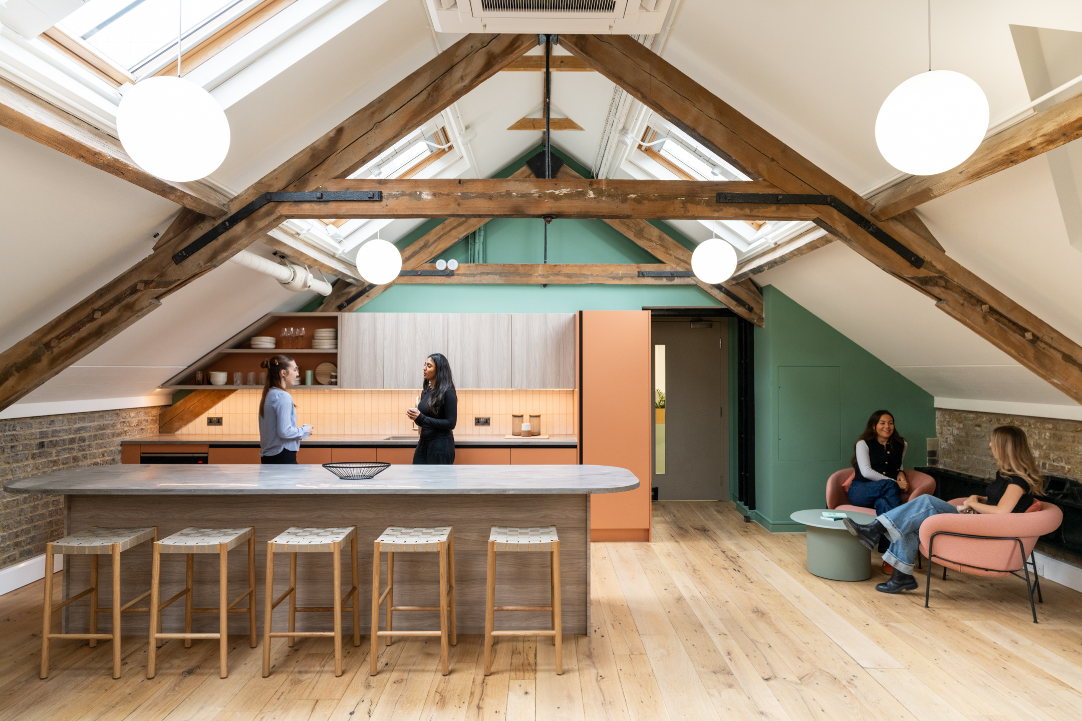 Loft style teapoint, with wooden beams being the focus point, with large ceiling windows bringing in lots of light into the space. The teapoint has high stools and an island.